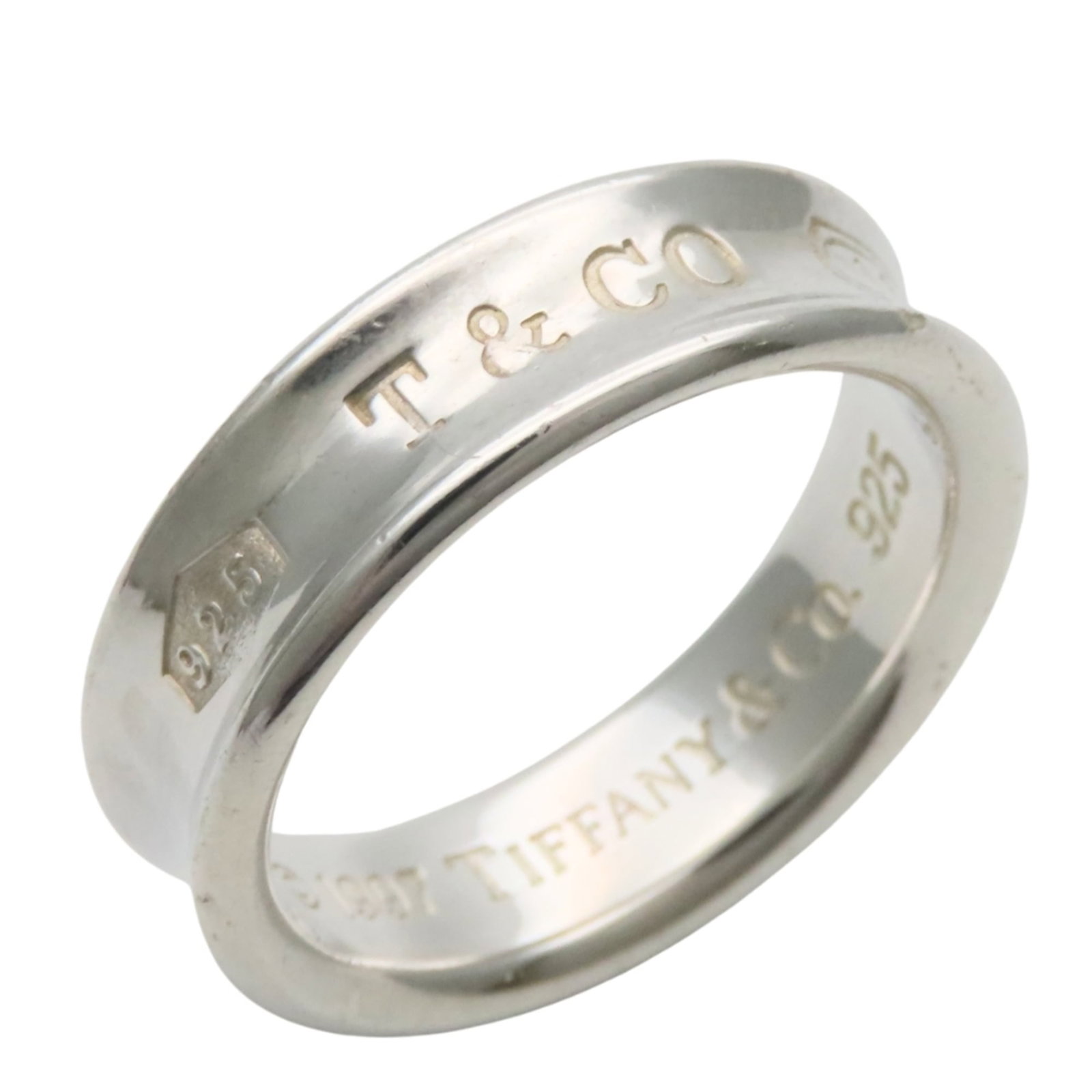 Tiffany Band Ring Silver 925: Tiffany Band Ring Silver 925 Silver 925 band ring from Tiffany, featuring a classic design in a durable and long-lasting silver alloy. The item shows signs of past use, with minor scratches and dirt v