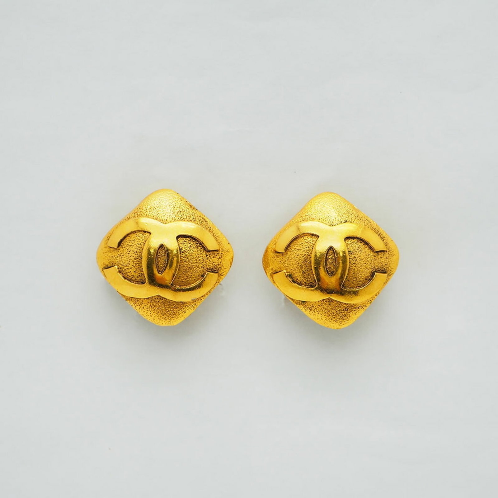 Chanel Clip Earrings: Chanel Clip Earrings Gold clip earrings from Chanel, measuring 23.00mm x 23.00mm, with traces of usage visible due to scratches and dirt. The condition shows signs of wear, but overall remains in good