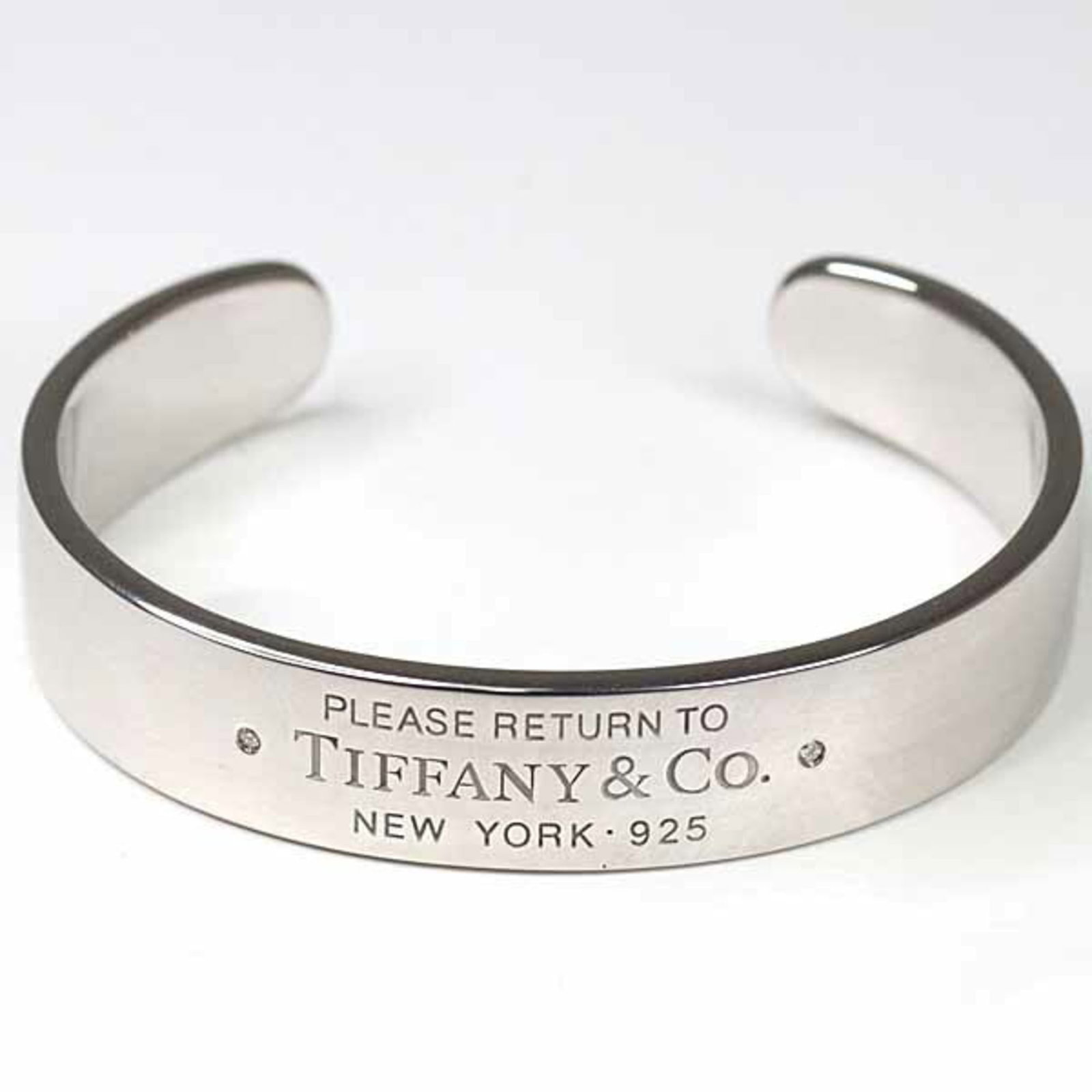Silver Bangle Tiffany: Silver Bangle Tiffany Silver Bangle Tiffany, made from high-quality 925 silver, features a sleek and sophisticated design. The bangle's silver finish has some minor scratches and dirt, but overall rem