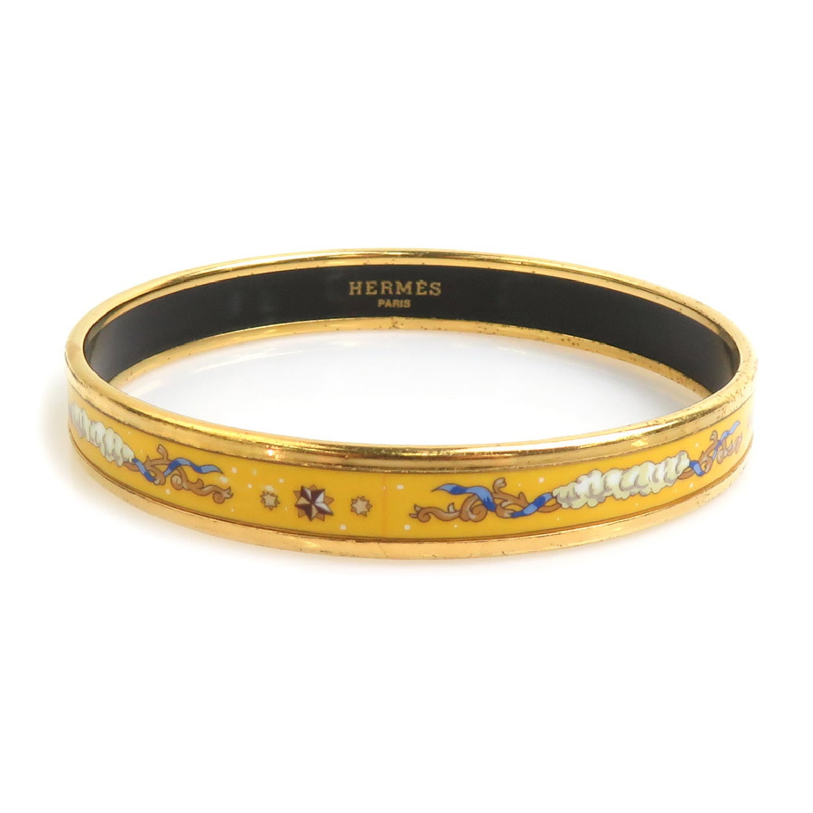 Metal enamel bangle by Hermes: Metal enamel bangle by Hermes Gold metal bangle with enamel details, measuring 19cm in length. The bangle bears signs of usage and has minor scratches and dirt. It is a used item in good condition. It