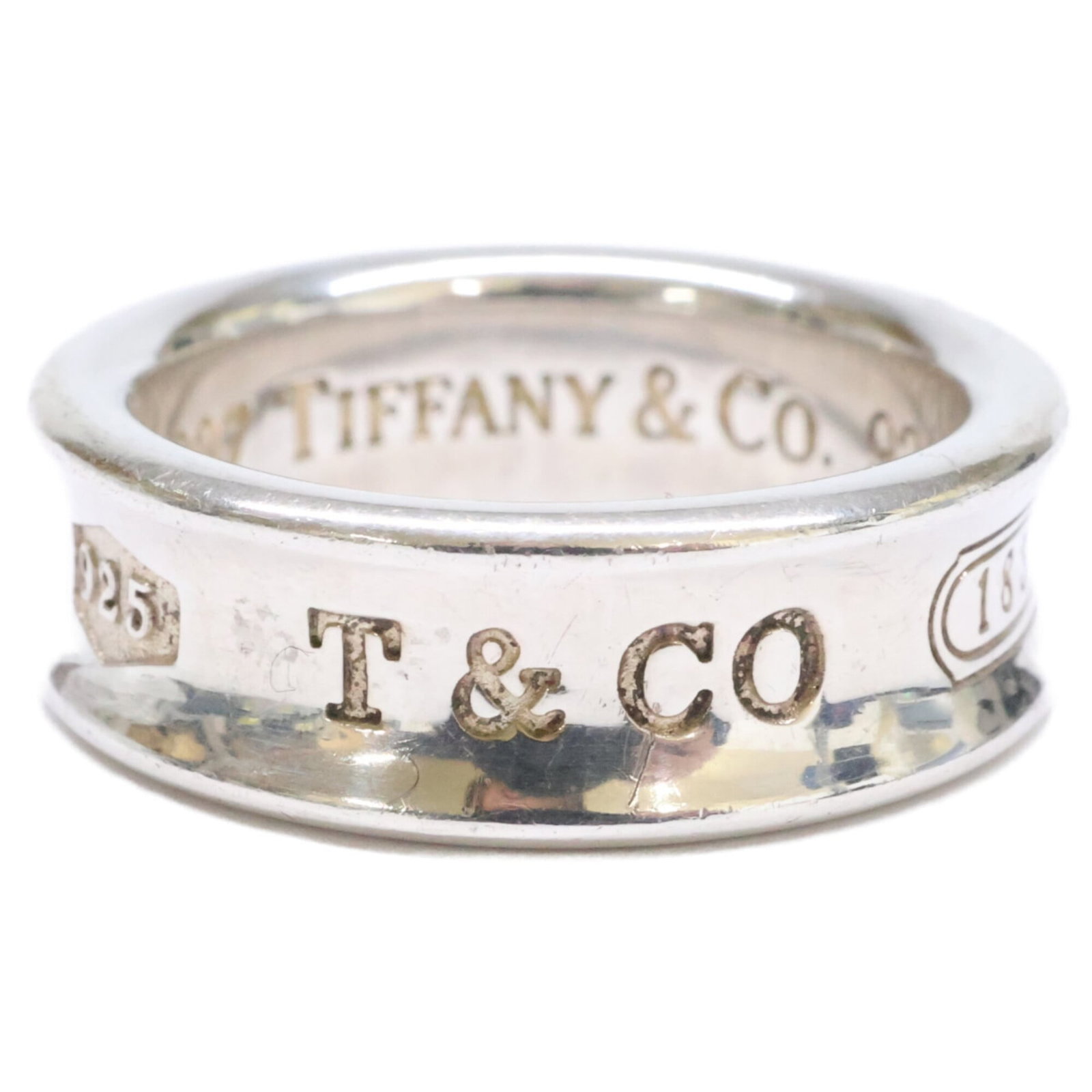 Tiffany Band Ring Silver 925: Tiffany Band Ring Silver 925 Silver 925 band ring from Tiffany, featuring a classic design with subtle wear and minor scratches. The item bears a signature but its origin is unknown. In good condition