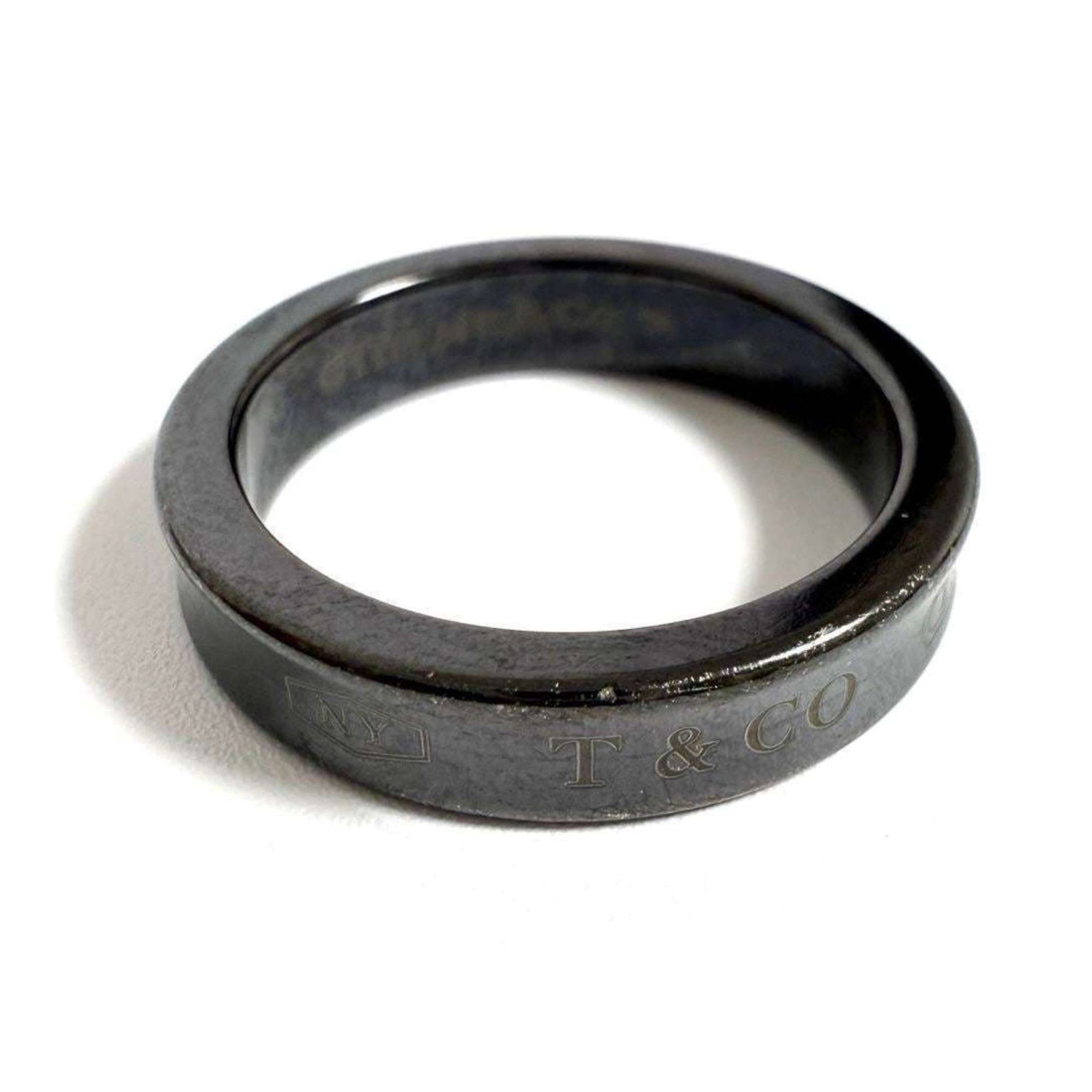 Tiffany Band Ring Titanium: Tiffany Band Ring Titanium Made from durable titanium, this Tiffany band ring offers a sleek and modern design. With its used condition featuring only minor traces of usage, it remains in very good