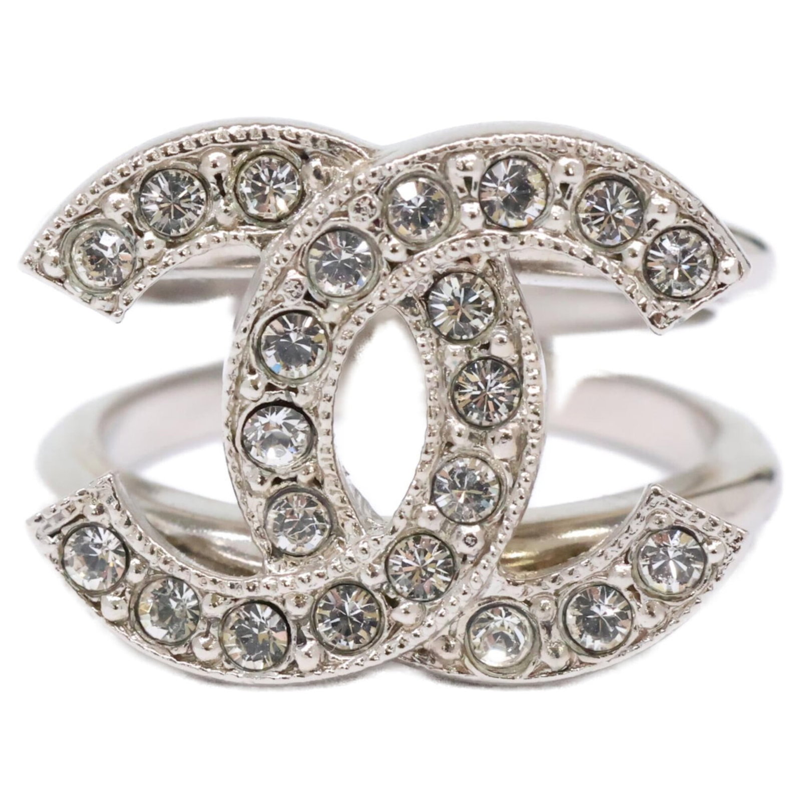 Metal Ring Chanel Band: Metal Ring Chanel Band The Chanel Band ring features a sleek silver metal band adorned with rhinestones, adding a touch of glamour to any outfit. This used band ring shows some signs of wear,