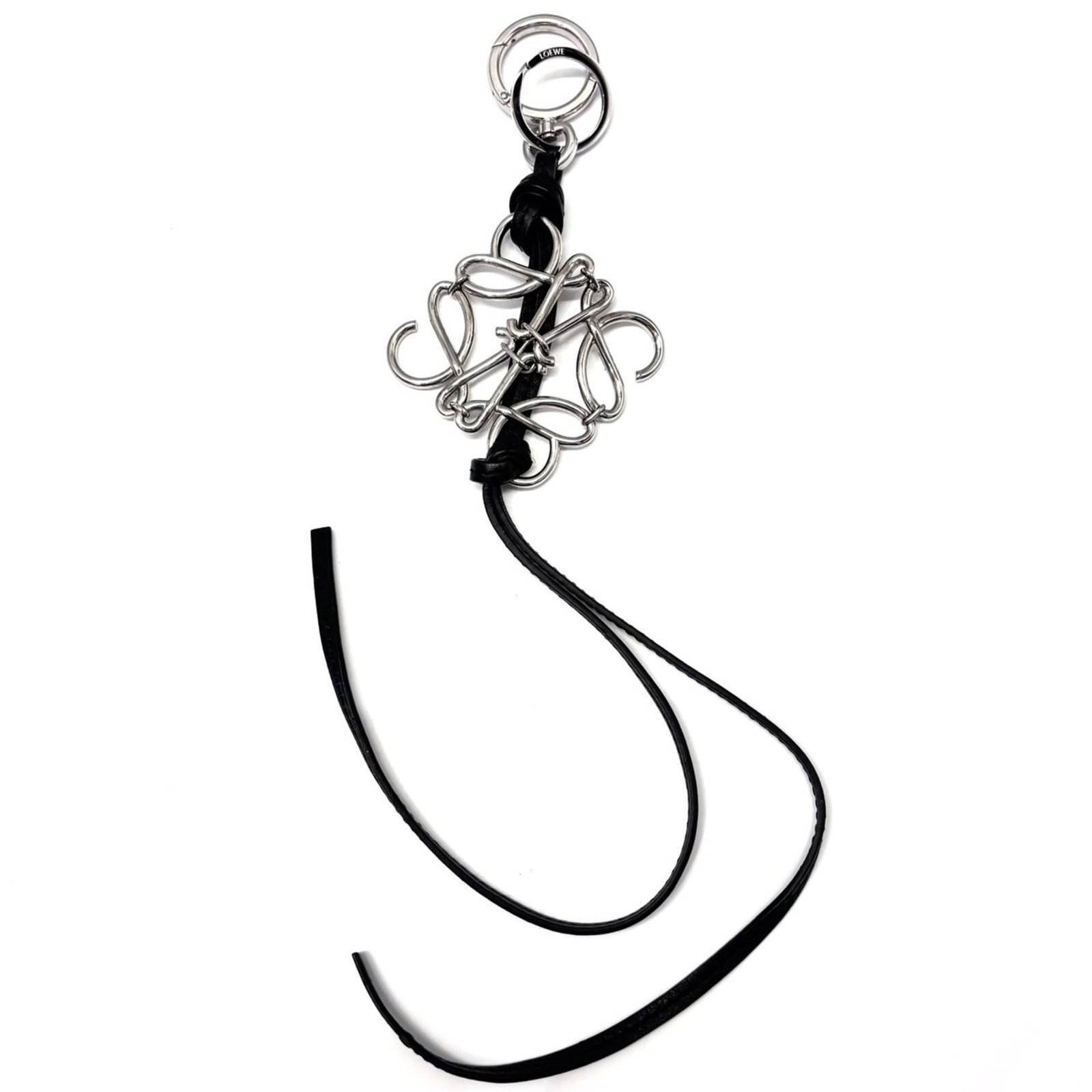 Handbag Charm Leather Metal of Loewe: Handbag Charm Leather Metal of Loewe Black Loewe handbag charm made from high-quality leather and metal, bearing a signature. The charm has some minor scratches and dirt, but overall remains in very