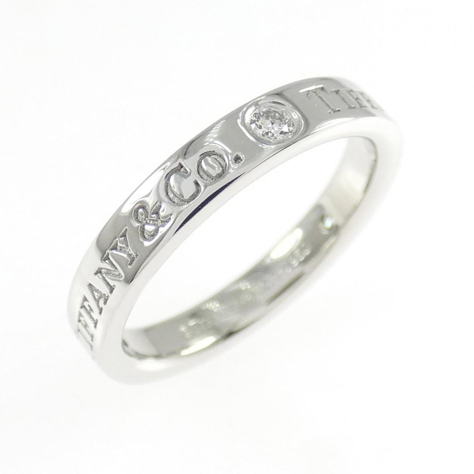 Platinum ring by Tiffany band: Platinum ring by Tiffany band Platinum ring by Tiffany features a diamond stone set in a band design. The item is made from platinum and has a us size of 4, with some minor scratches and dirt visible 