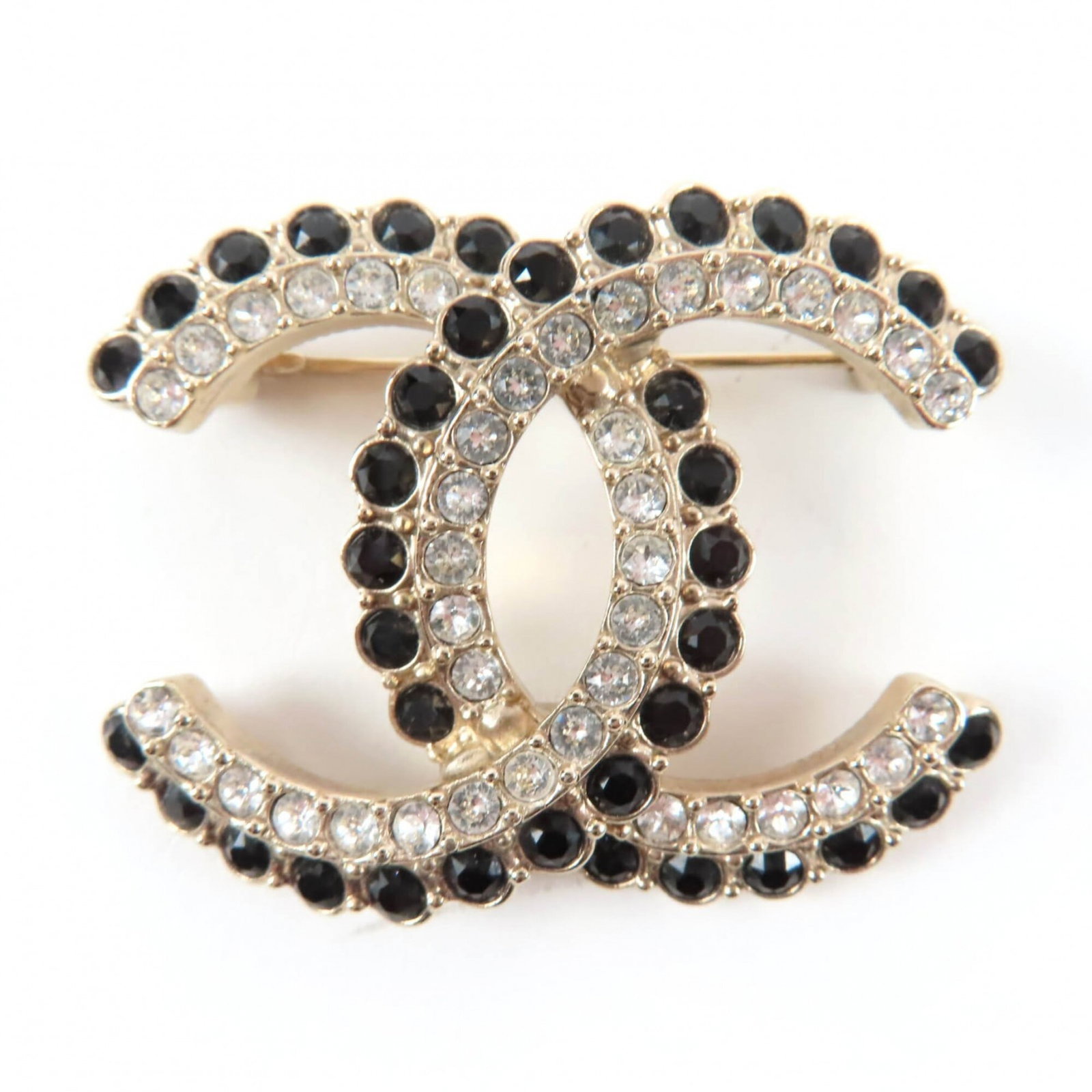Chanel Brooch: Chanel Brooch A sleek and sophisticated black Chanel brooch, featuring gold accents, measures 3.5cm x 4.5cm in size. This used item has hardly any traces of usage, showcasing its condition as very goo