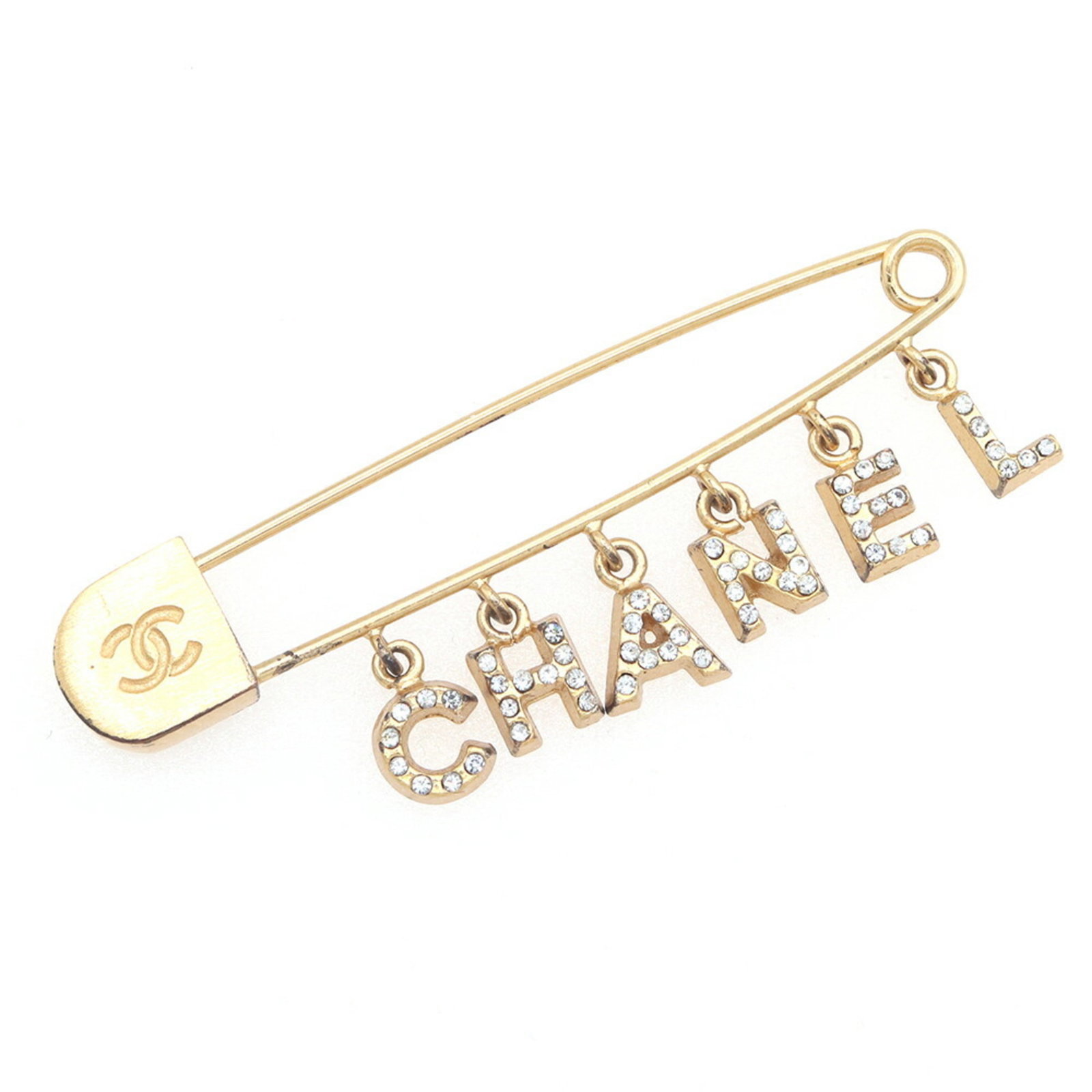 Metal pin by Chanel: Metal pin by Chanel Metal pin by Chanel, featuring a rhinestone stone and measuring 2cm x 5.7cm, bears the signature of the brand. The item has been used, with traces of usage visible, including scrat