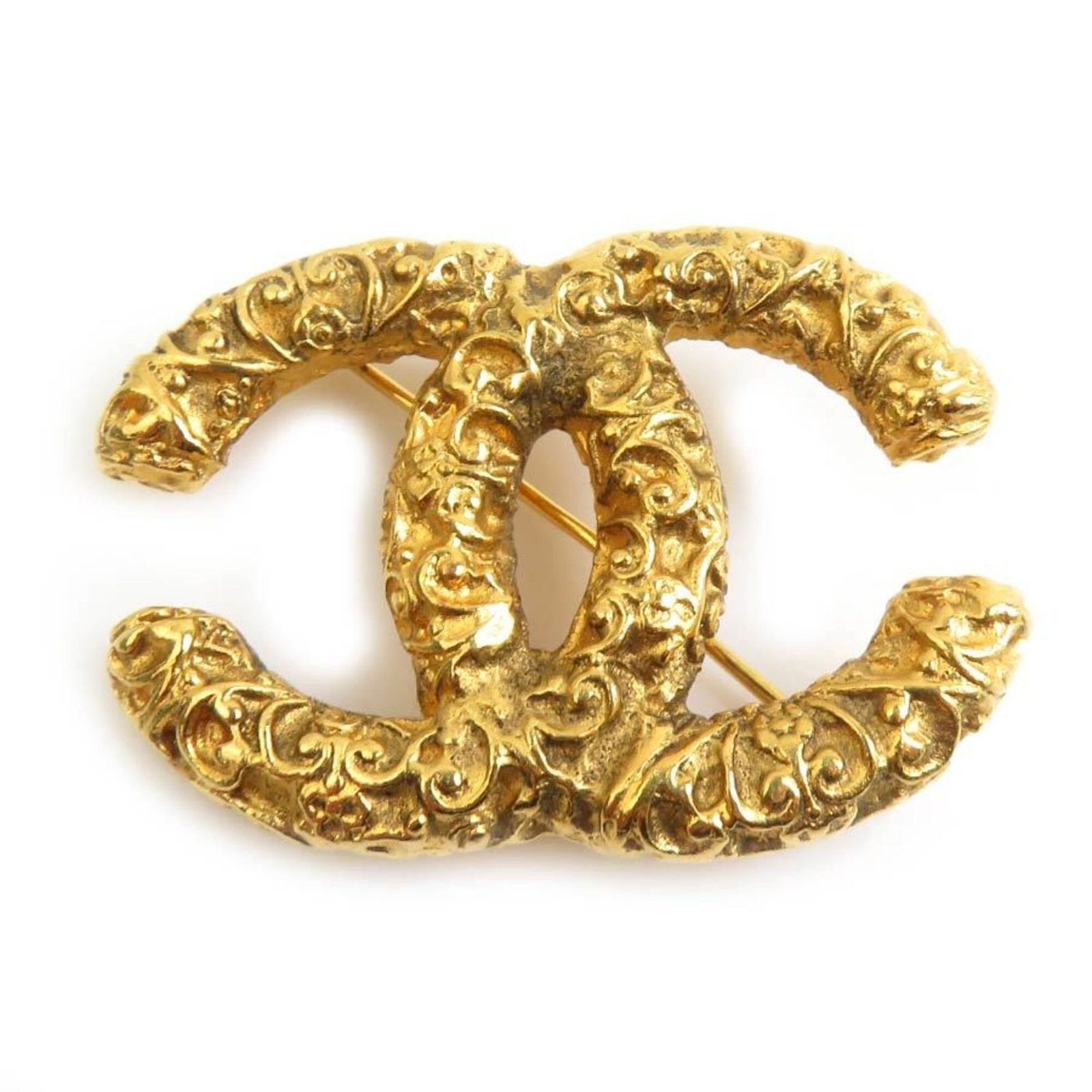 Metal brooch by Chanel: Metal brooch by Chanel This gold metal brooch by Chanel boasts a classic design, bearing the iconic brand's signature style. With its 3cm x 4.2cm dimensions and subtle signs of wear, it presents a