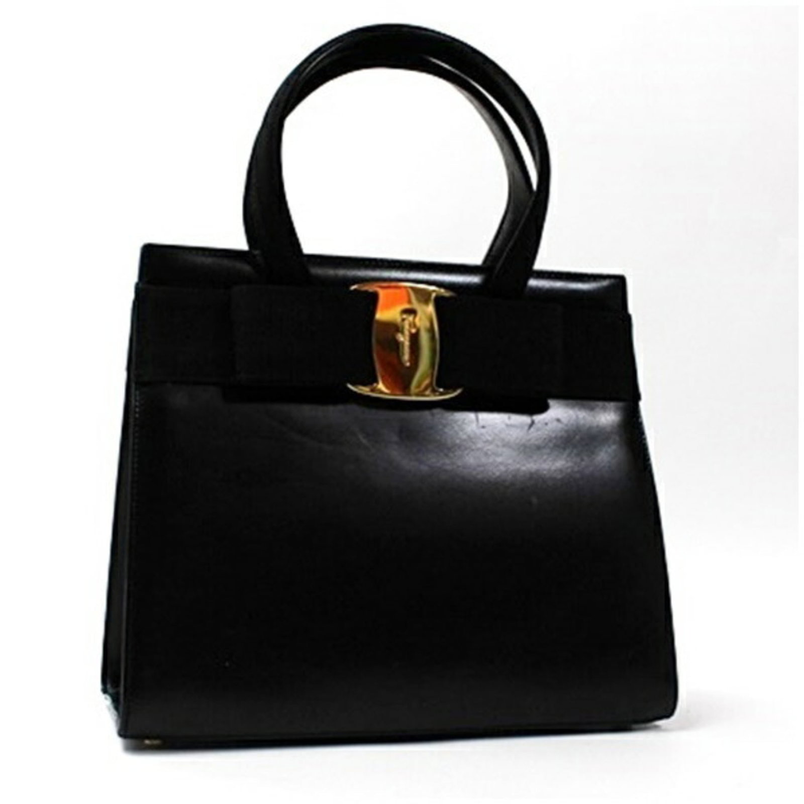 Handbag Leather by Salvatore Ferragamo: Handbag Leather by Salvatore Ferragamo Black leather handbag by Salvatore Ferragamo, featuring gold hardware and a classic design. The bag has been used and shows signs of wear, including scratches