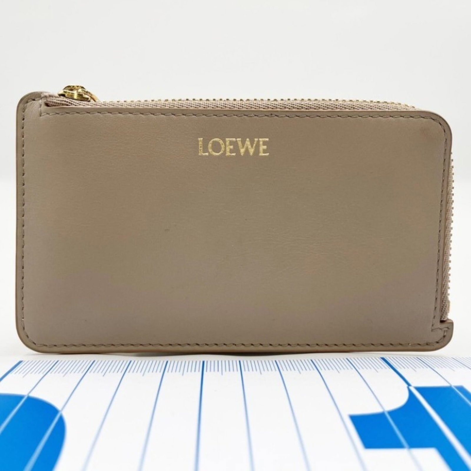 Card case leather: Card case leather Used beige calfskin leather card case with some traces of usage, minor scratches and dirt. The condition is very good overall, reflecting a few signs of wear. This card case bears a 