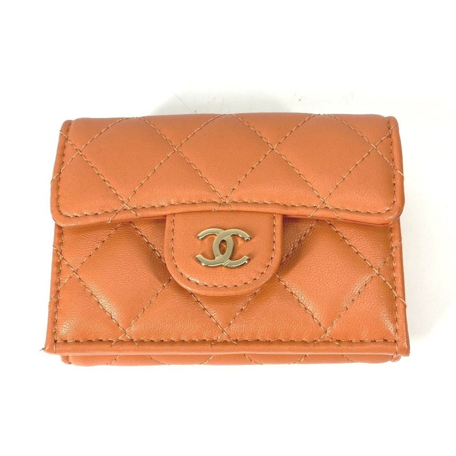 Leather Tri-Fold Wallet By Chanel: Leather Tri-Fold Wallet By Chanel This iconic Chanel tri-fold wallet boasts a vibrant orange lambskin exterior, showcasing the brand's signature style. Made from high-quality leather, it features a