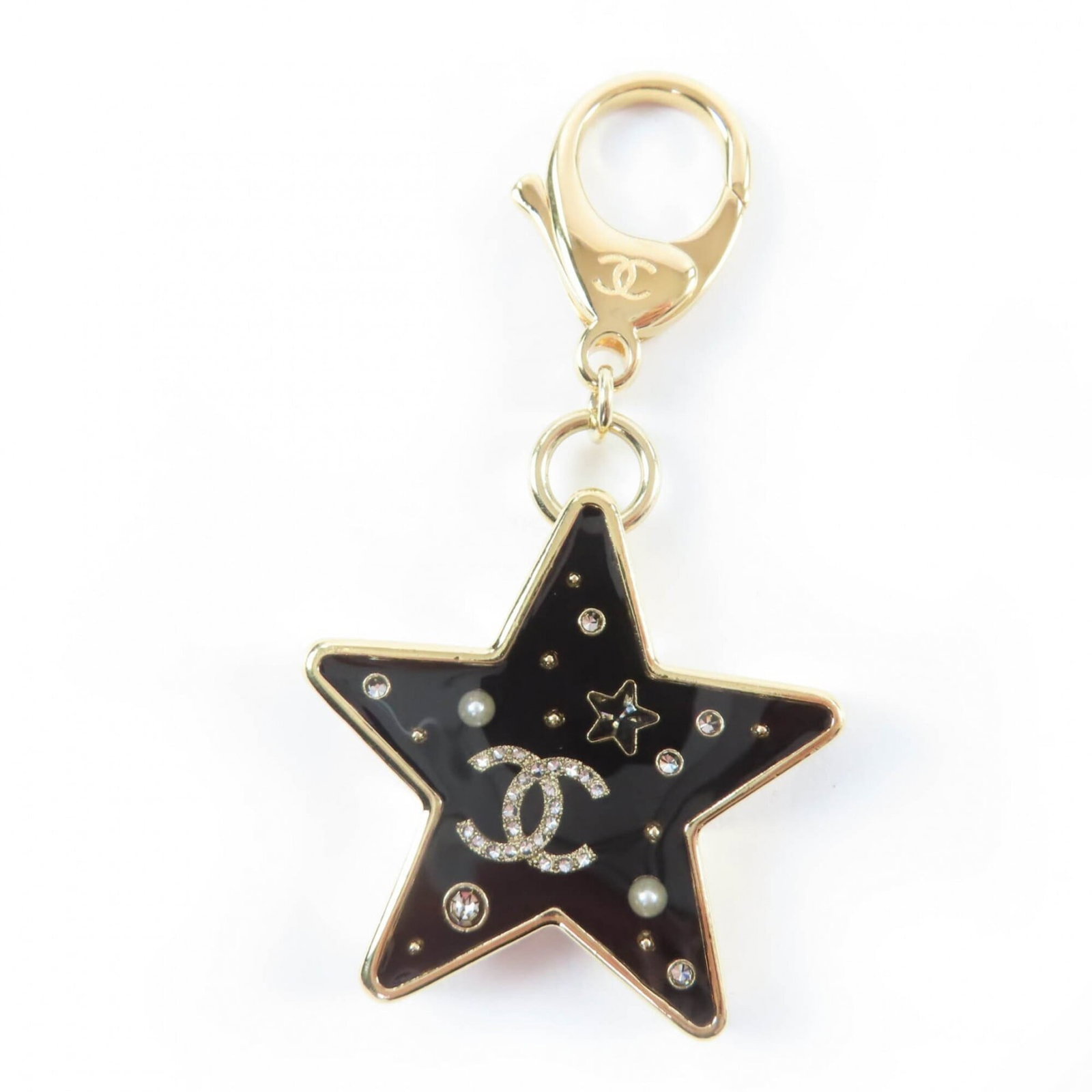 Keyring of Chanel: Keyring of Chanel Black and gold charm keyring from Chanel, featuring a 4cm x 4cm / 1.57'' x 1.57'' design. The item has some scratches and dirt, but remains in very good condition with only a few tra