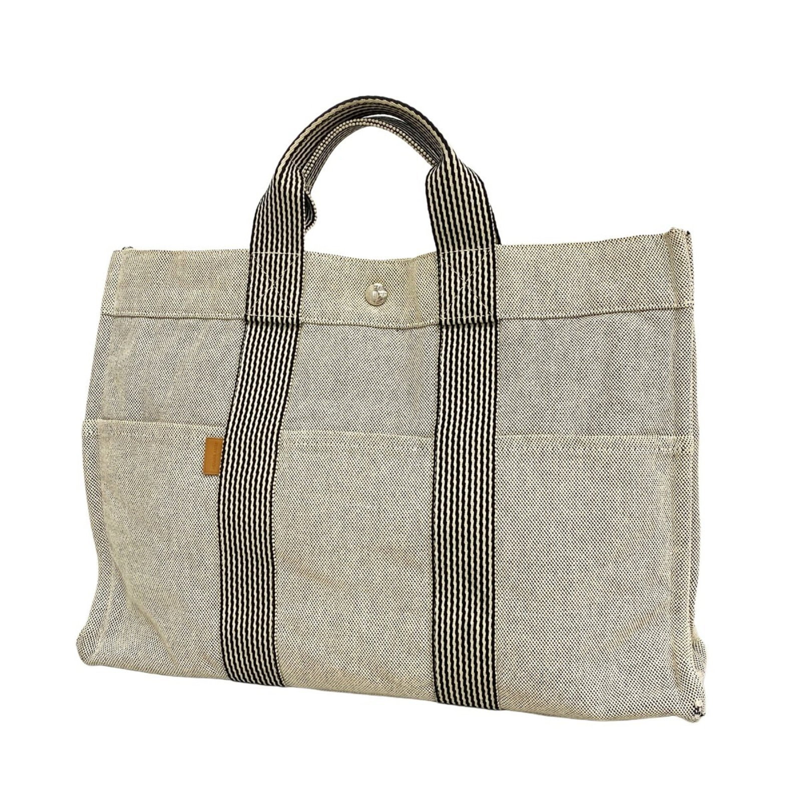 Canvas tote bag by Hermes: Canvas tote bag by Hermes Canvas tote bag by Hermes, featuring a timeless gray color and sleek silver hardware. This versatile bag boasts a sturdy canvas material and measures 30cm x 42cm x 10cm.