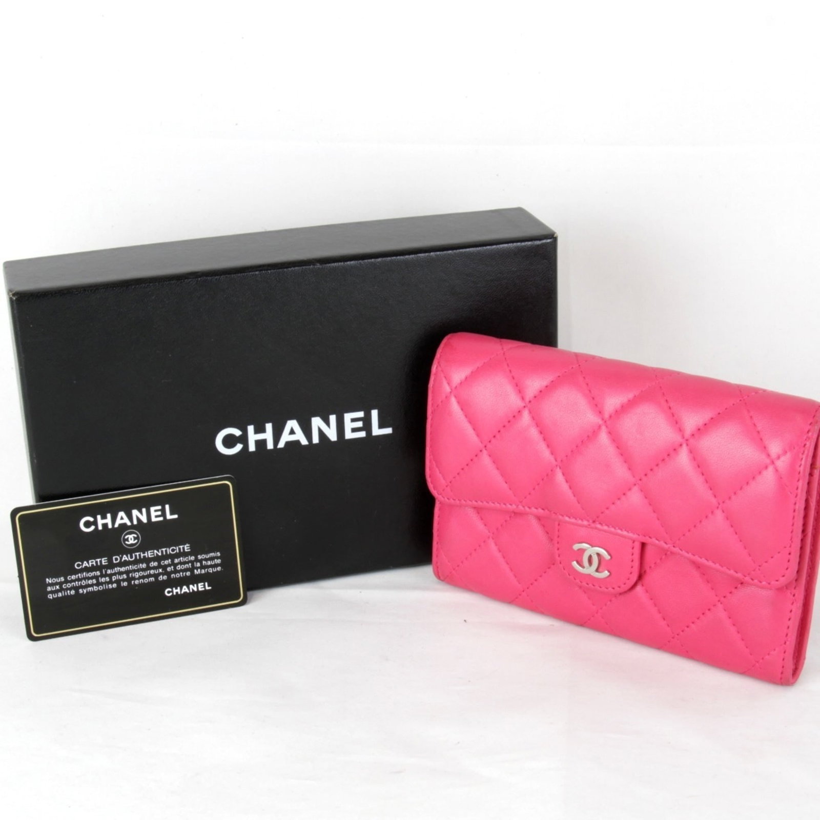 Leather Bi Fold Wallet By Chanel: Leather Bi Fold Wallet By Chanel Pink leather bi-fold wallet by Chanel, featuring a classic design with a subtle pink hue. The wallet has a slight wear and tear, with traces of usage visible, but
