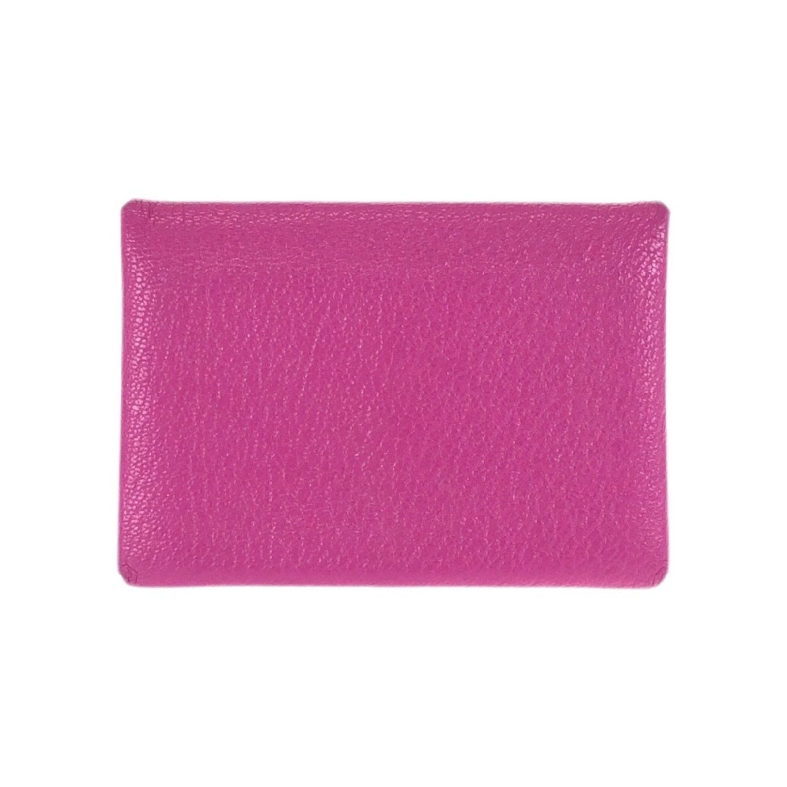 Chevre leather card case by Hermes: Chevre leather card case by Hermes Chevre leather card case by Hermes features a soft pink hue and elegant design. The material bears traces of usage, with scratches and dirt visible, but remains in g