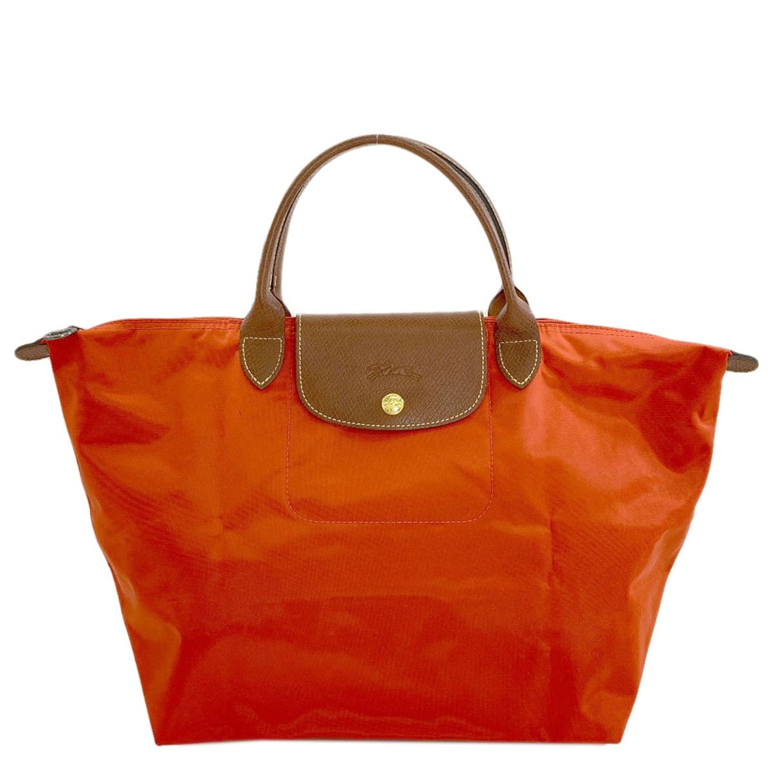 Nylon Le Pliage Handbag Longchamp: Nylon Le Pliage Handbag Longchamp Orange Nylon Le Pliage Handbag by Longchamp. This vibrant handbag boasts a durable nylon exterior and the iconic Le Pliage design, known for its versatility and