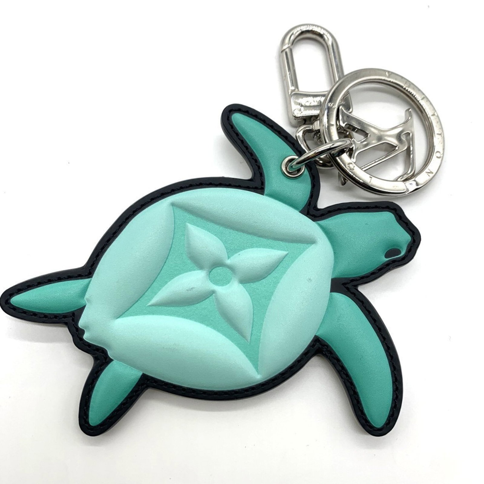 Louis Vuitton keyring leather metal: Louis Vuitton keyring leather metal This Louis Vuitton keyring features a striking green leather and metal design, measuring 10.5cm x 9.5cm in size. With a few traces of usage visible, it retains its 