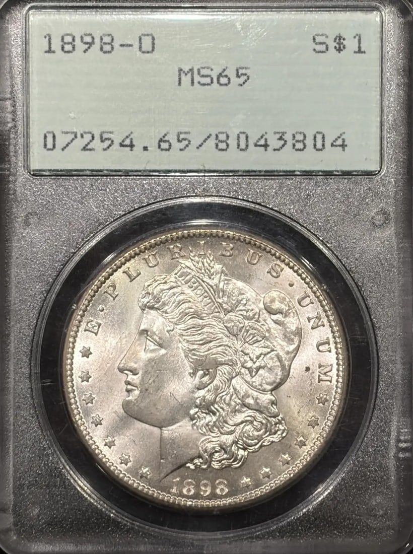 1898-O MORGAN DOLLAR PCGS MS65 RATTLER OGH VERY PQ: 1898-O MORGAN DOLLAR PCGS MS65 RATTLER OGH VERY PQ The 1898-O Morgan Dollar, graded MS65 by PCGS, boasts a stunning condition with only minor imperfections. This rare coin, certified by the