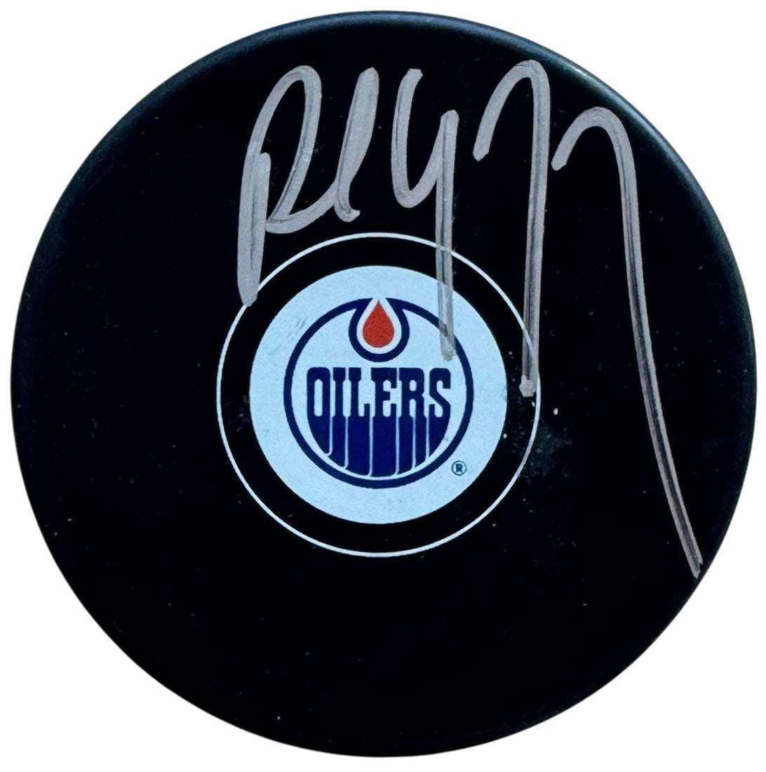 Coffey Paul Autographed Beckett Oilers Edmonton Logo Puck: Coffey Paul Autographed Beckett Oilers Edmonton Logo Puck Signed in silver sharpie across the front, this Beckett Professional Graded Edmonton Oilers logo puck bears the distinctive mark of hockey leg