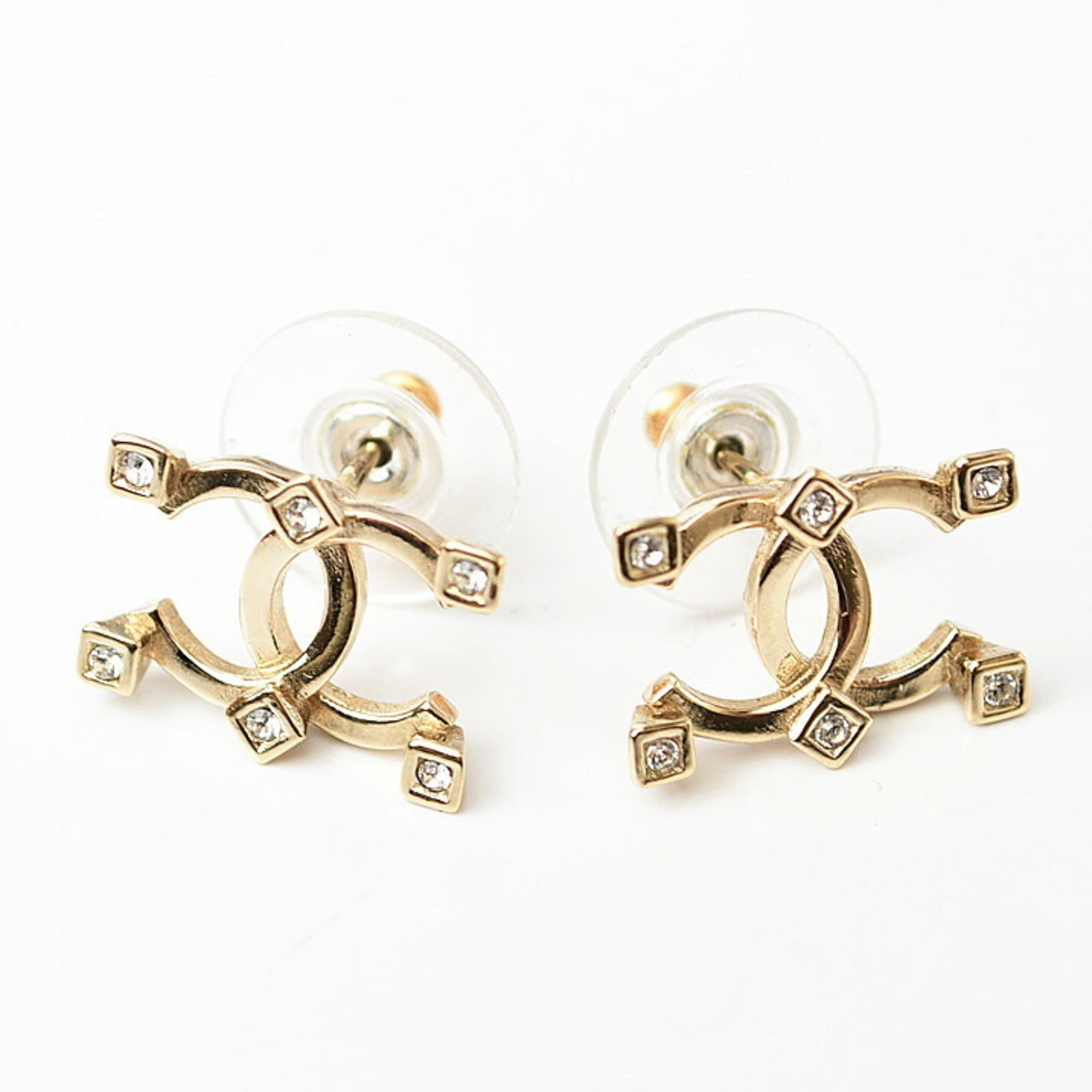Metal Stud Chanel Earrings: Metal Stud Chanel Earrings Gold stud earrings from Chanel, featuring rhinestone stones and presented in a box. These metal earrings measure 11.00mm x 15.00mm and are made of gold material. The item