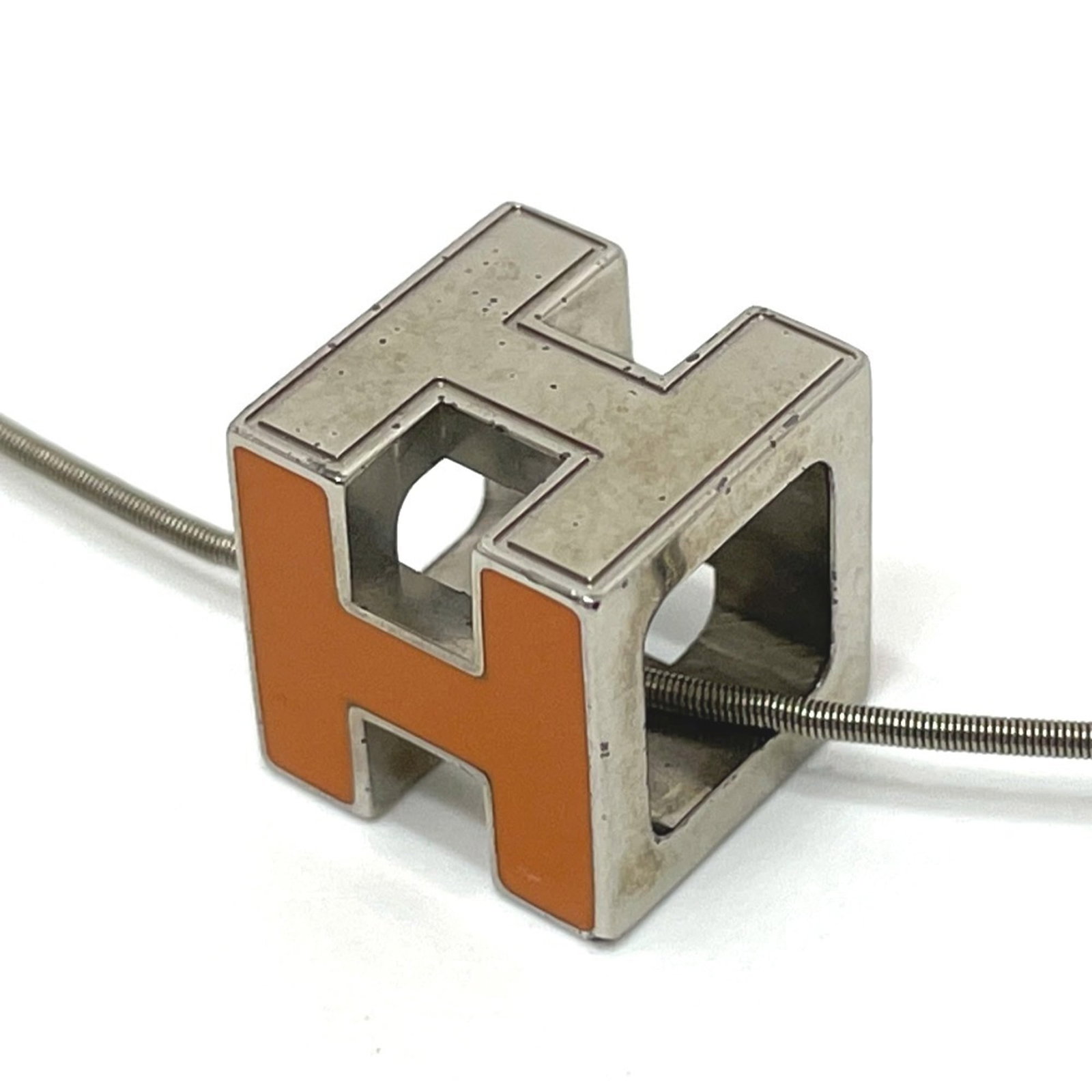 Metal Orange Women's Silver Cartier D'Ache In Necklace Hermes Cube: Metal Orange Women's Silver Cartier D'Ache In Necklace Hermes Cube Orange metal necklace with silver details from Hermes, featuring the iconic Cage d'h design. The pendant measures 11mm x 11mm and