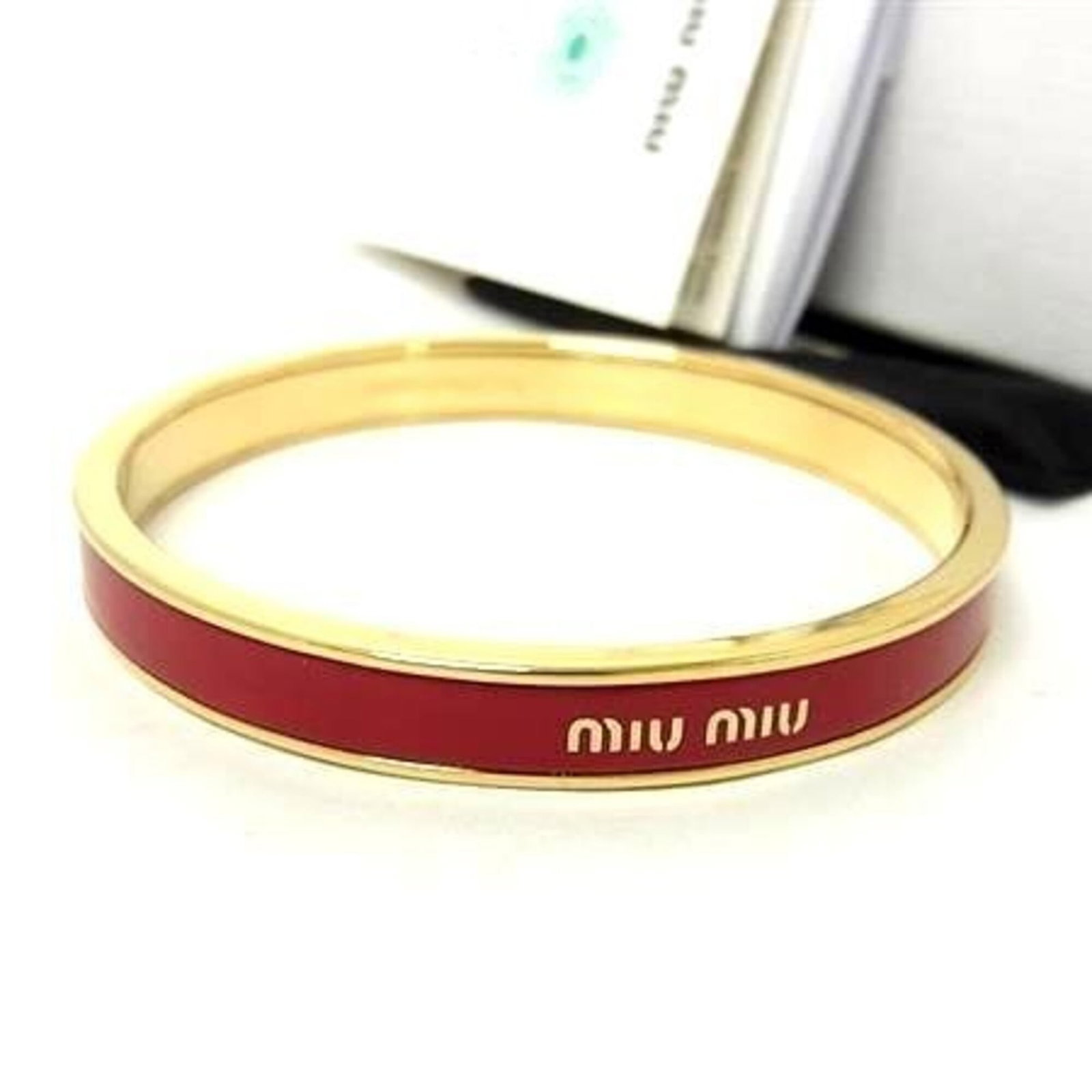 Metal bangle Miu: Metal bangle Miu Metal bangle Miu in gold and red color, measuring 20cm in length. This Italian-made bangle showcases its metal material and distinctive design. Made by the renowned brand Miu Miu,