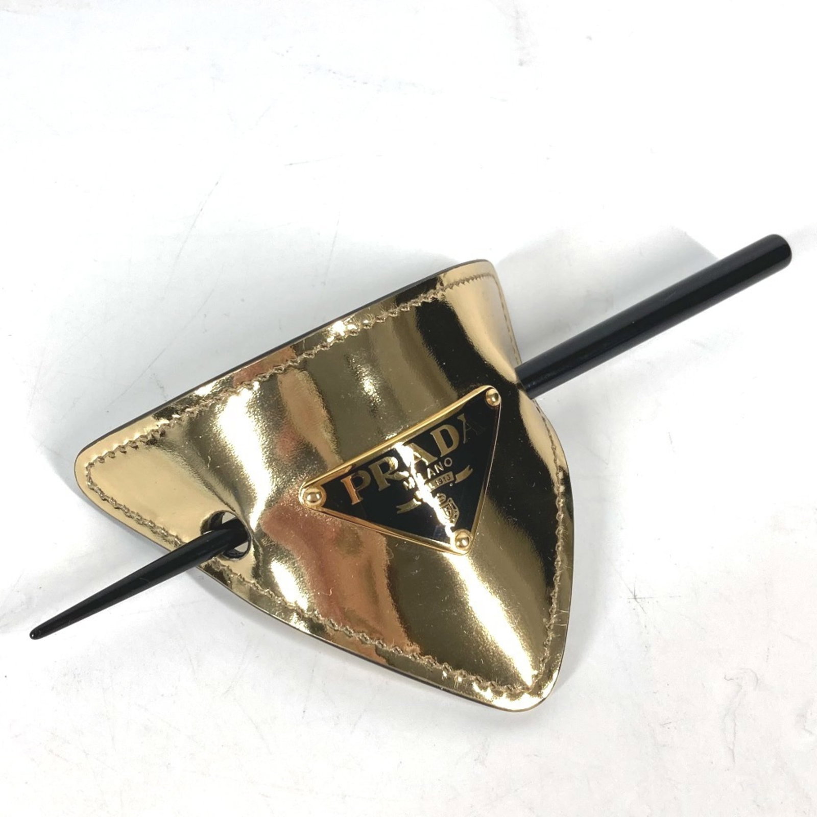 Kanzashi Leather by Prada: Kanzashi Leather by Prada Kanzashi Leather by Prada is a sleek and sophisticated accessory, crafted from high-quality leather in black with gold accents. The item measures 16.5cm x 6.49'' and comes