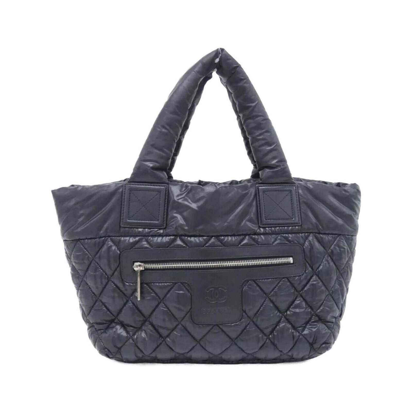 Nylon handbag by Chanel: Nylon handbag by Chanel Chanel's iconic nylon handbag boasts sleek black and silver hardware, perfectly complementing its modern design. Measuring 24cm x 42cm x 15cm, it offers a compact yet stylish o