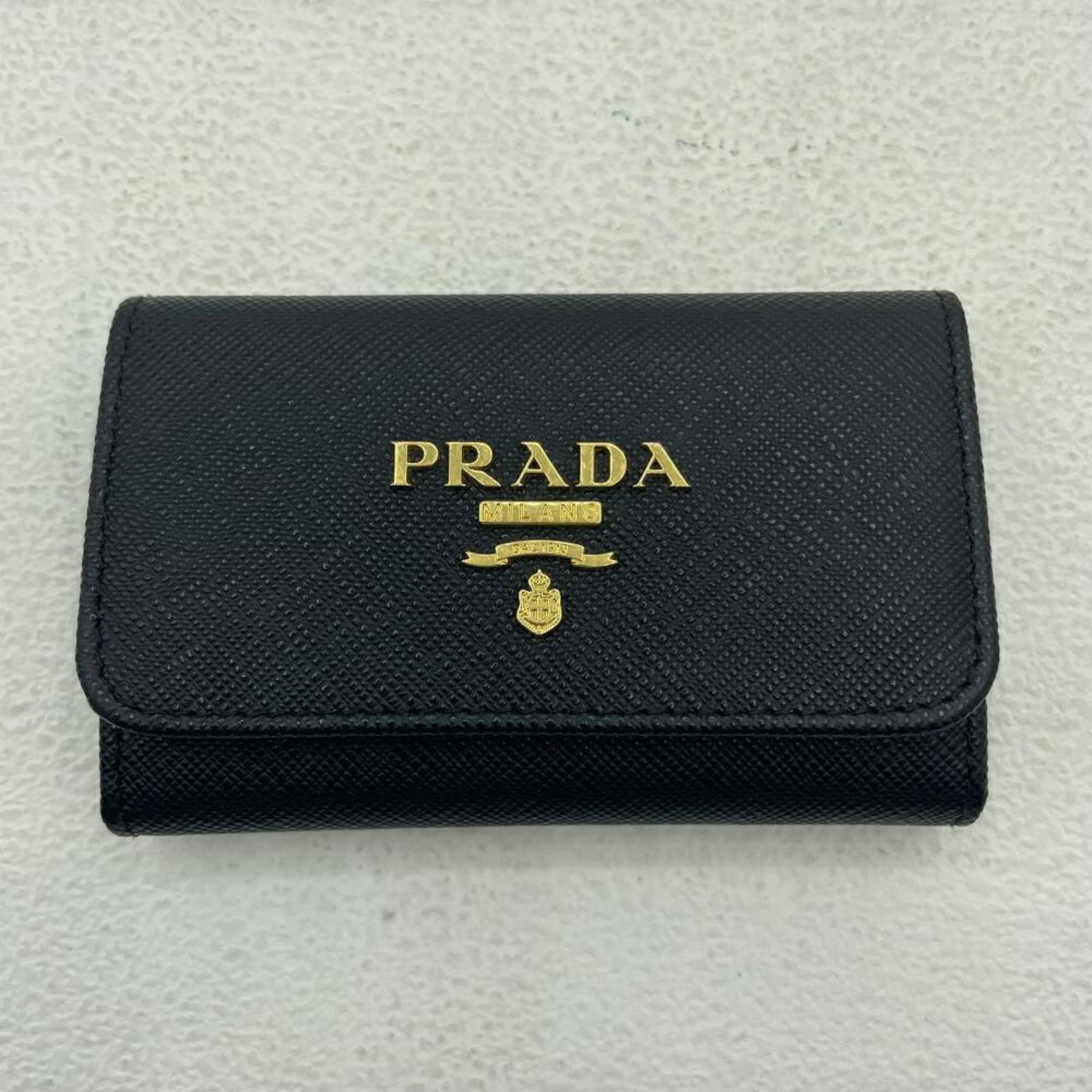 Keycase Leather by Prada: Keycase Leather by Prada The Prada Saffiano Keycase Leather boasts a sleek design with four spacious key hooks, perfectly sized for everyday use. Made from high-quality leather, its compact dimensions