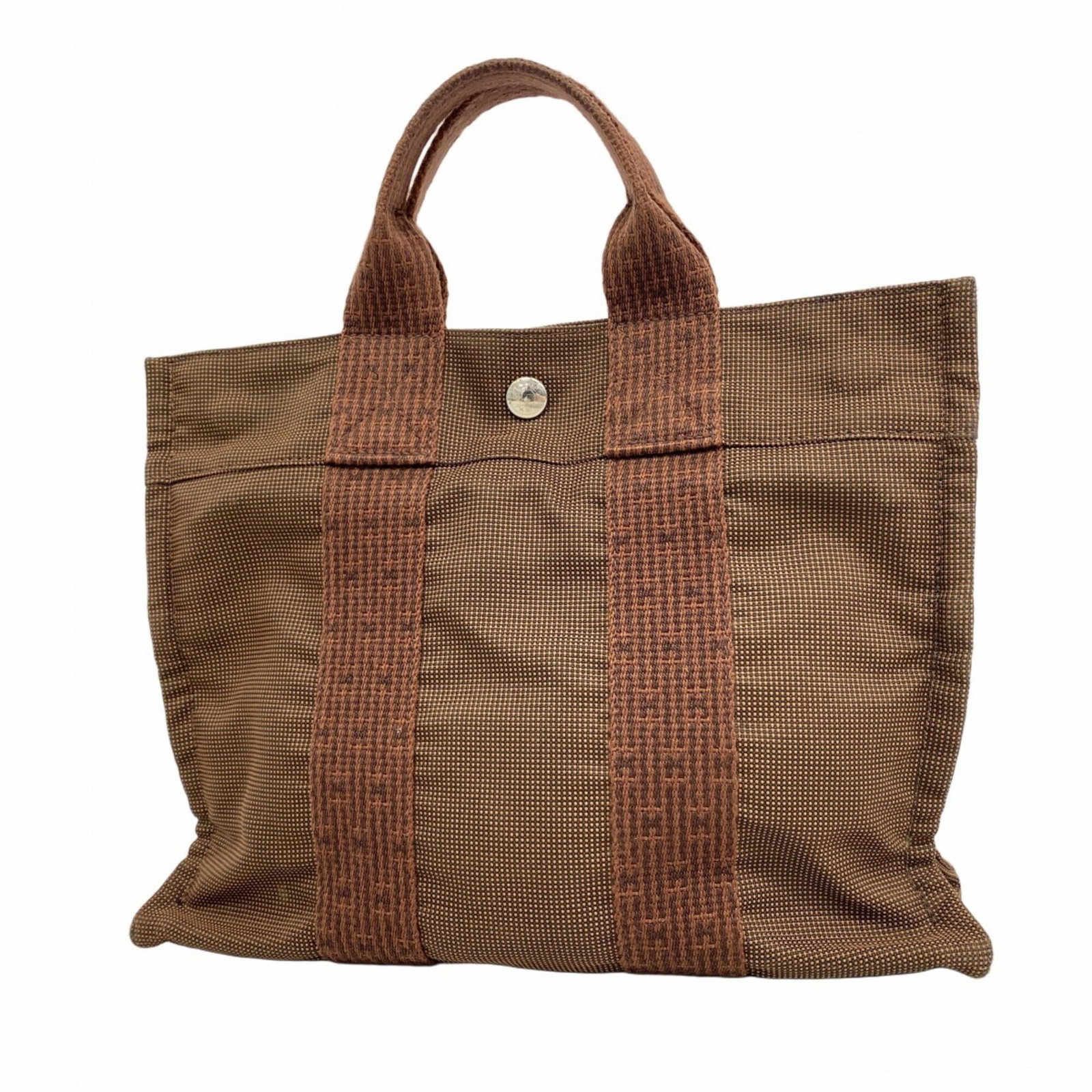Hermes Tote Bag Canvas: Hermes Tote Bag Canvas Canvas tote bag from Hermes, featuring brown canvas material and silver hardware. This classic design measures 25cm x 30.5cm x 8cm and has a sleek, timeless look. The signature 