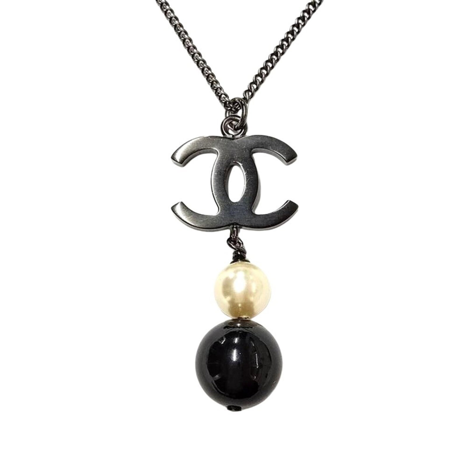 Coco Chanel B14B Black Metal Long Gold Faux Pearl Necklace: Coco Chanel B14B Black Metal Long Gold Faux Pearl Necklace Black metal necklace with long gold chain and artificial pearl pendant, bearing the Chanel B14B signature. This elegant piece features a slee