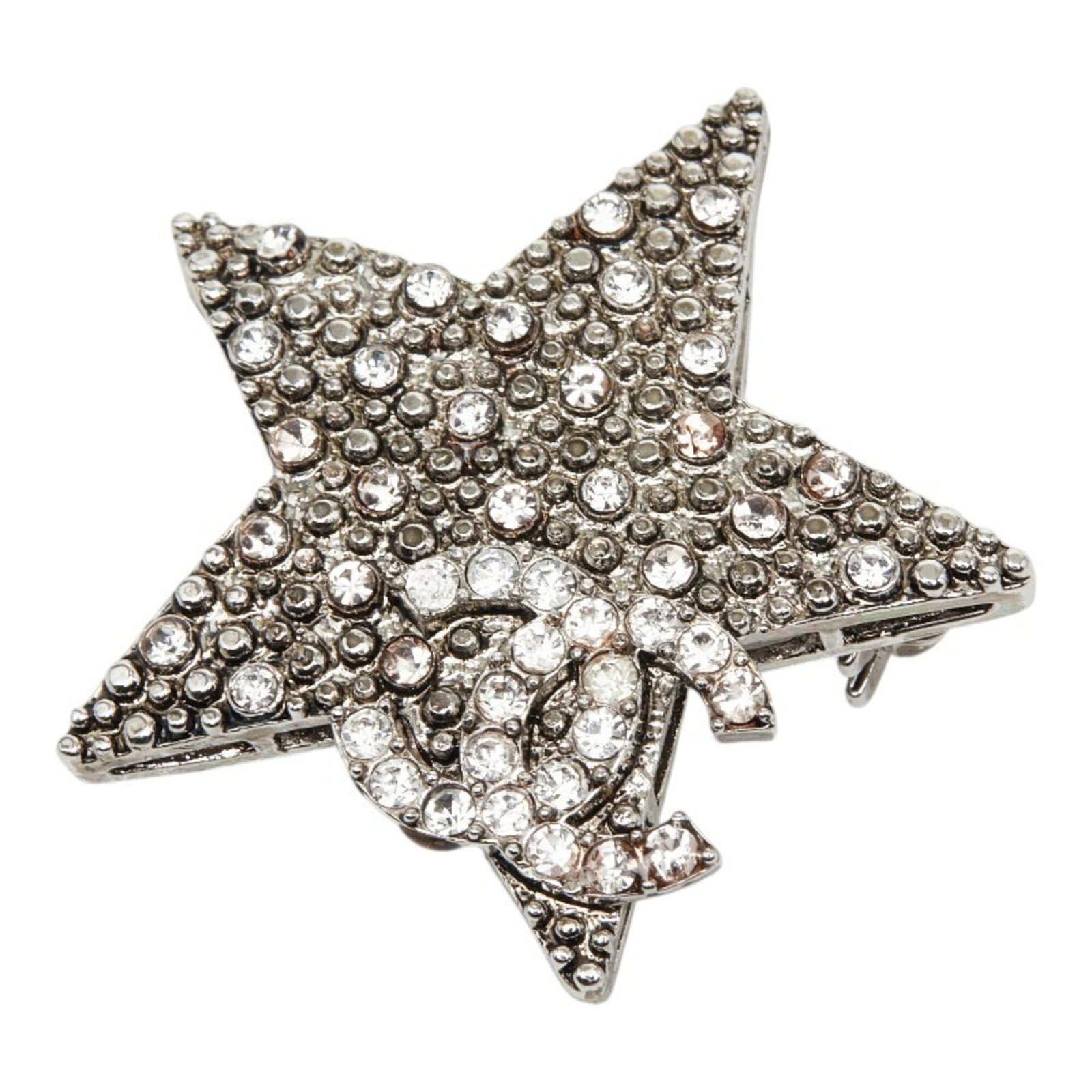 Metal brooch by Chanel: Metal brooch by Chanel Silver metal brooch by Chanel, featuring rhinestone stone and measuring 4.37cm x 4.47cm in size. This elegant piece showcases the iconic style of the renowned fashion brand.