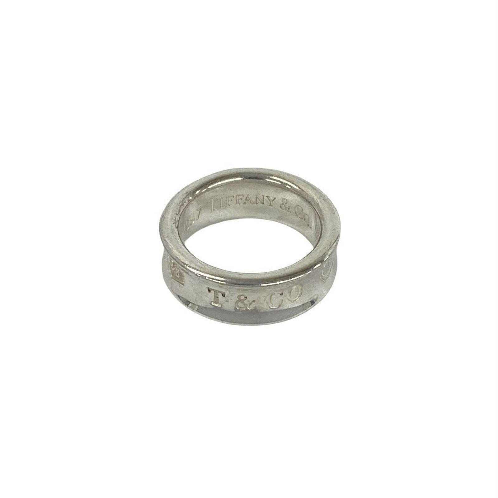 Silver band ring Tiffany 925: Silver band ring Tiffany 925 Silver band ring Tiffany 925 features a sleek, silver design with a US size 4 fit. Made from high-quality sterling silver (925), this band ring offers a touch of understat