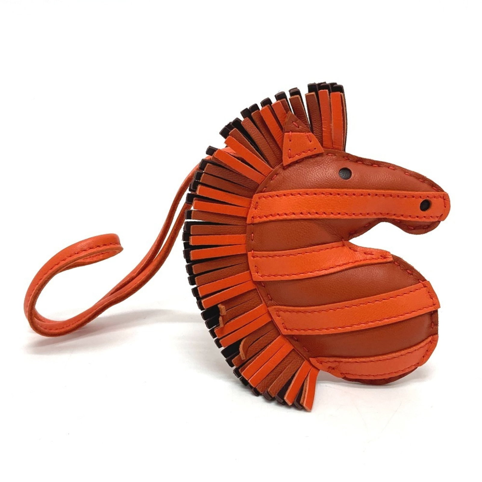 Handbag Hermes leather charm: Handbag Hermes leather charm The Hermes leather charm is a small, intricately designed accessory made from lambskin leather in the vibrant color orange. Measuring just 10.60mm x 9.20mm x 1.00mm, it co