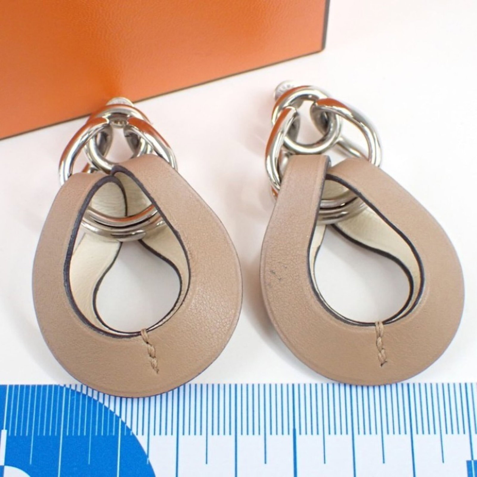 Swift Hermes Leather Metal Stud Earrings: Swift Hermes Leather Metal Stud Earrings Swift Hermes Leather Metal Stud Earrings are crafted from metal and feature Swift leather, with a brown and white color combination. The earrings measure 60.00