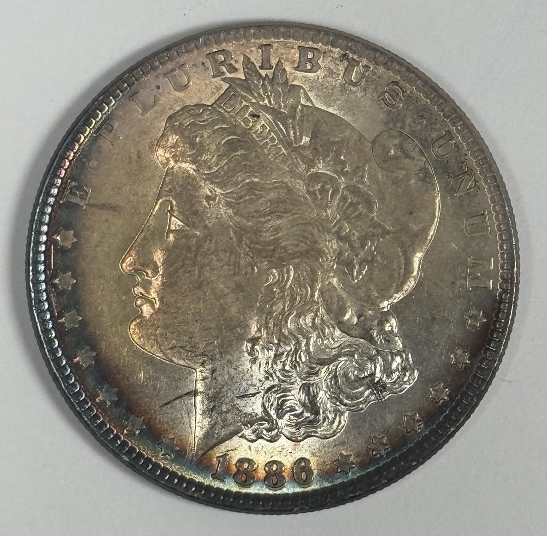 1886 MORGAN DOLLAR RAW UNCIRCULATED - RAINBOW TONING: 1886 MORGAN DOLLAR RAW UNCIRCULATED - RAINBOW TONING The 1886 Morgan dollar boasts a stunning rainbow toning effect, adding an extra layer of visual appeal to its already impressive silver composition