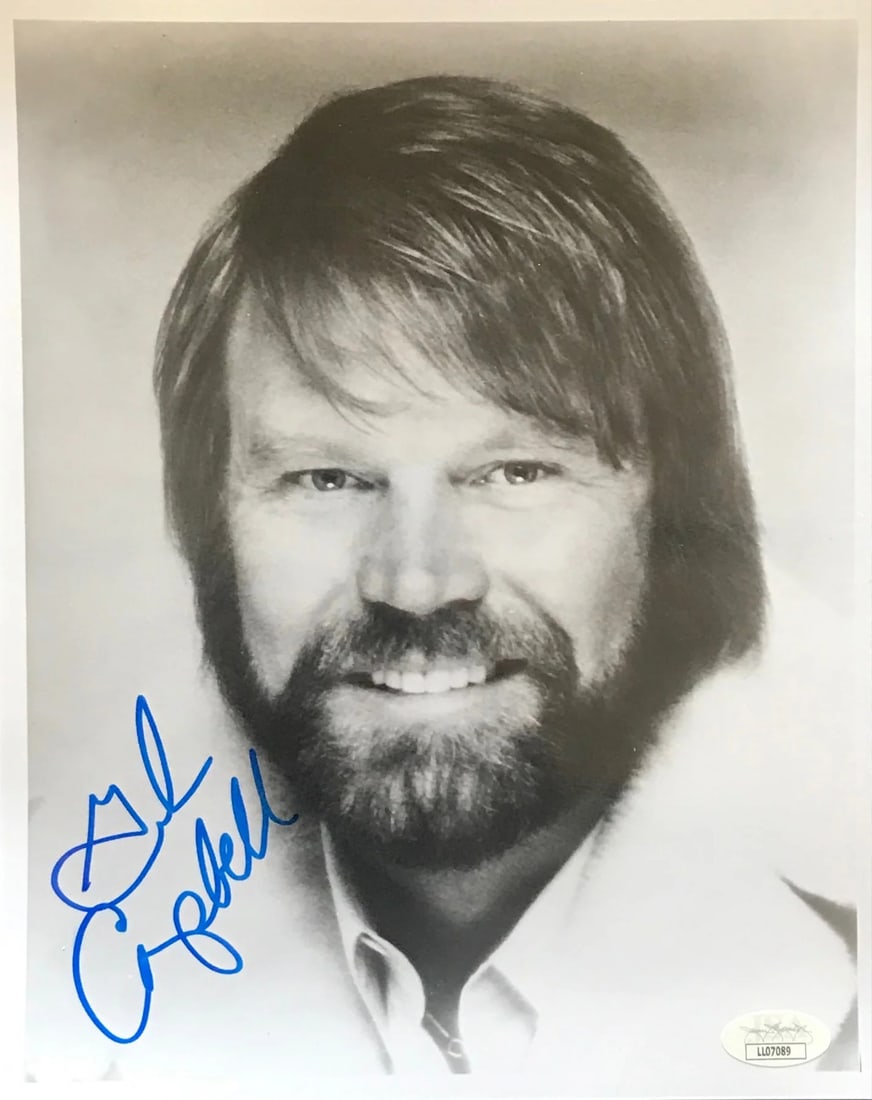 Campbell Glen Autographed Photo 8x10 by JSA: Campbell Glen Autographed Photo 8x10 by JSA Glen Campbell's iconic image is captured in an 8x10 photo, signed by the legendary artist himself in blue pen. This rare and unique piece bears the unmistak
