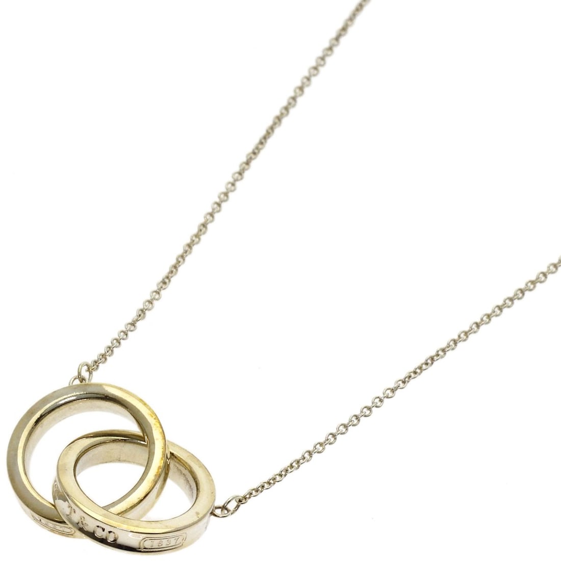 Silver Interlocking Circle Necklace Tiffany&Co.: Silver Interlocking Circle Necklace Tiffany&Co. Silver Interlocking Circle Necklace from Tiffany&Co. boasts a sleek silver design with no main stone, making it a simple yet elegant accessory. Measurin