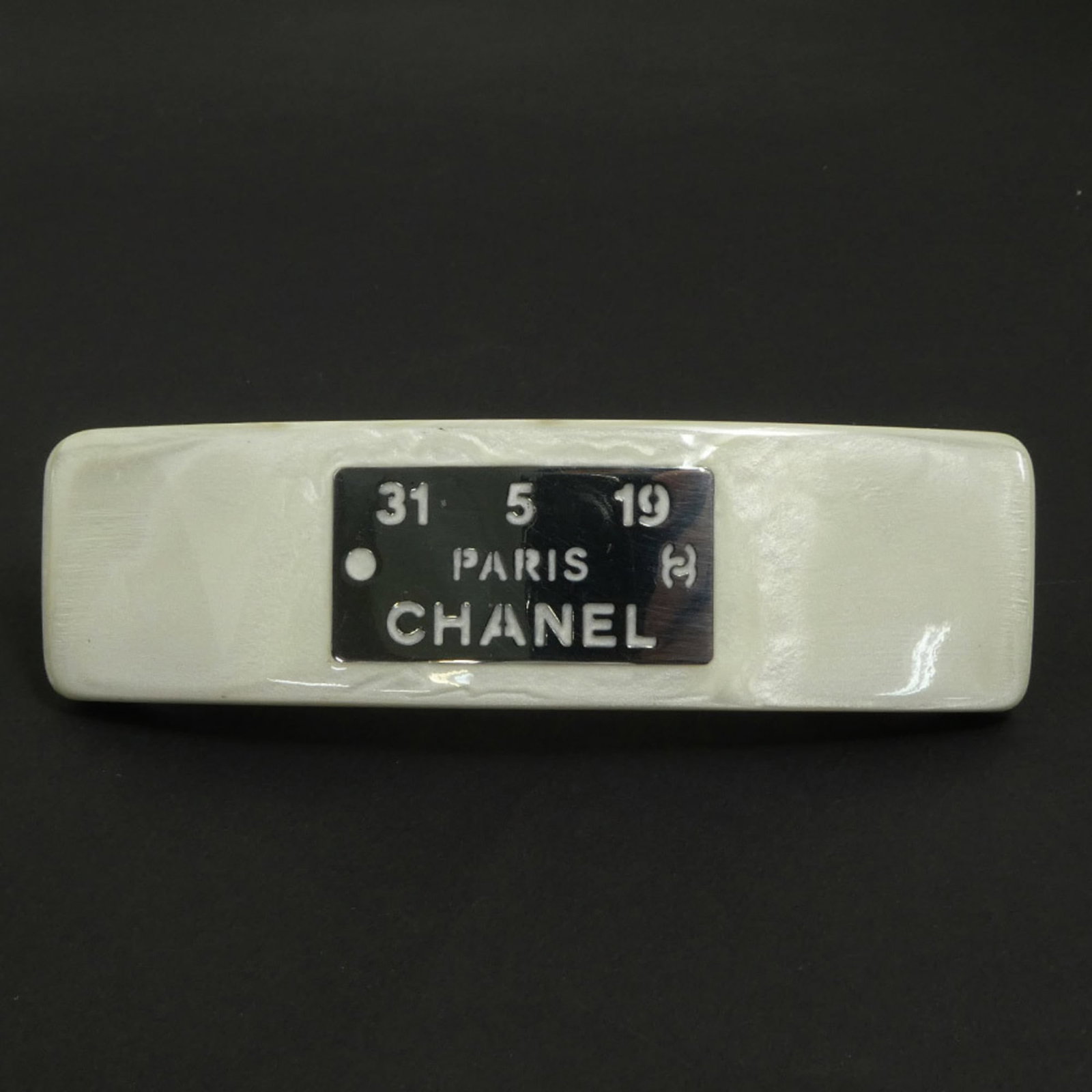 Metal resin barrette by Chanel: Metal resin barrette by Chanel Metal resin barrette by Chanel boasts sleek, off-white and silver hues in its metal and resin design. The compact size, measuring 2.6cm x 9.5cm, makes it a stylish