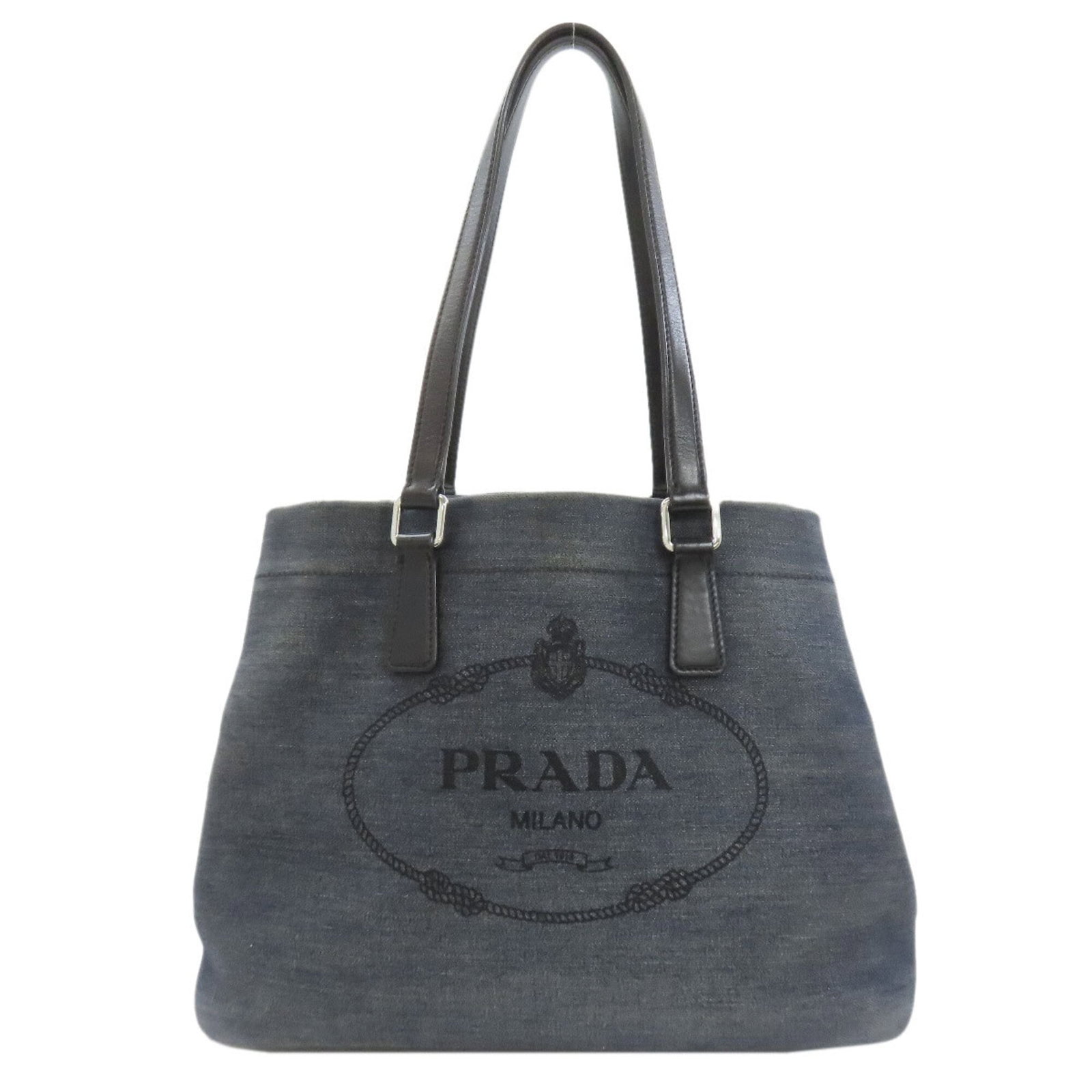 Denim Tote Bag Prada: Denim Tote Bag Prada Blue denim tote bag from Prada, measuring 23cm x 27cm x 14cm. The bag's denim material and blue color make it a distinctive piece. This small-sized tote bag bears a signature.