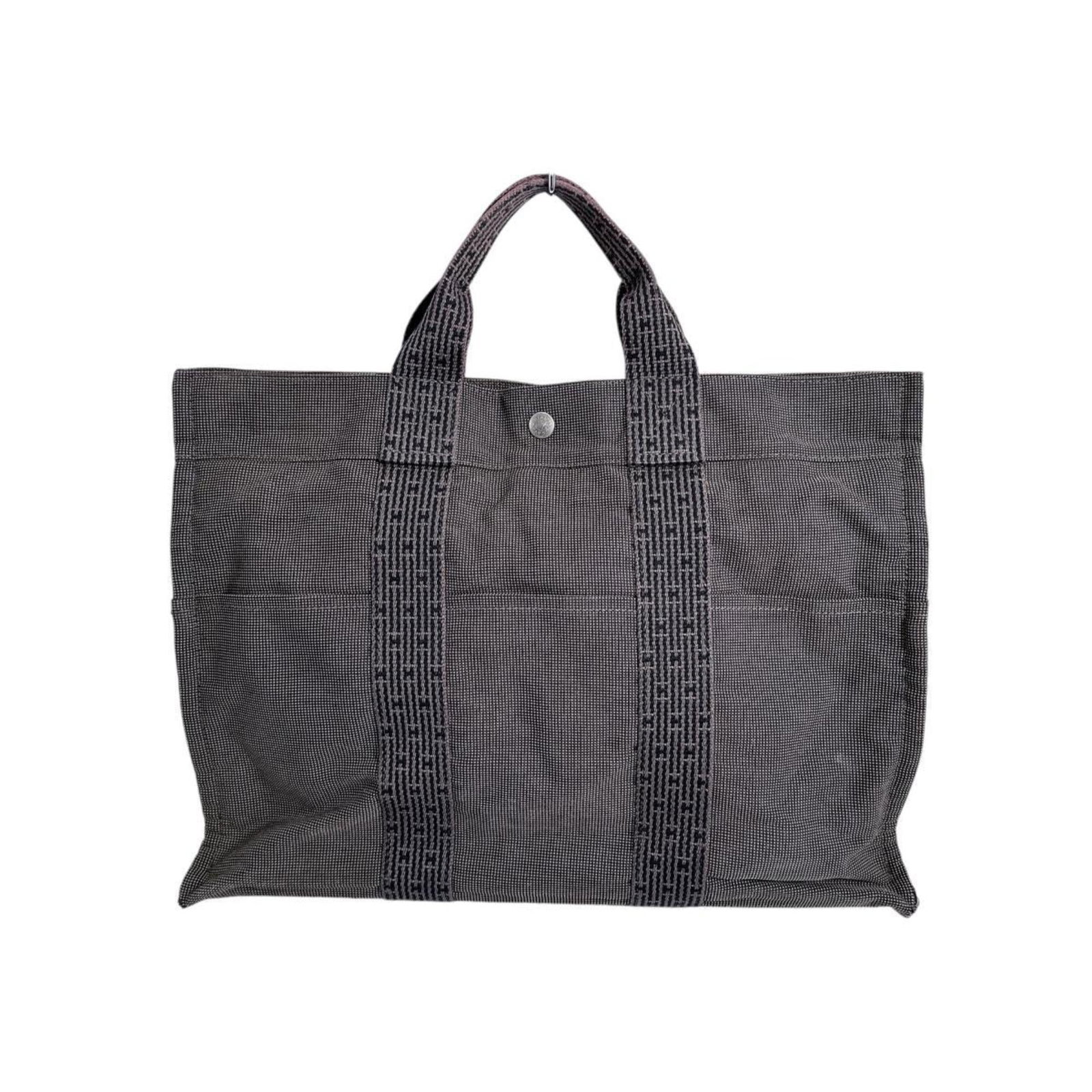 Canvas Hermes Tote Bag: Canvas Hermes Tote Bag Canvas Hermes Tote Bag in Gray. Made from high-quality canvas, this tote bag features a classic design with a zipper closure and padlock for added security. With its timeless gr