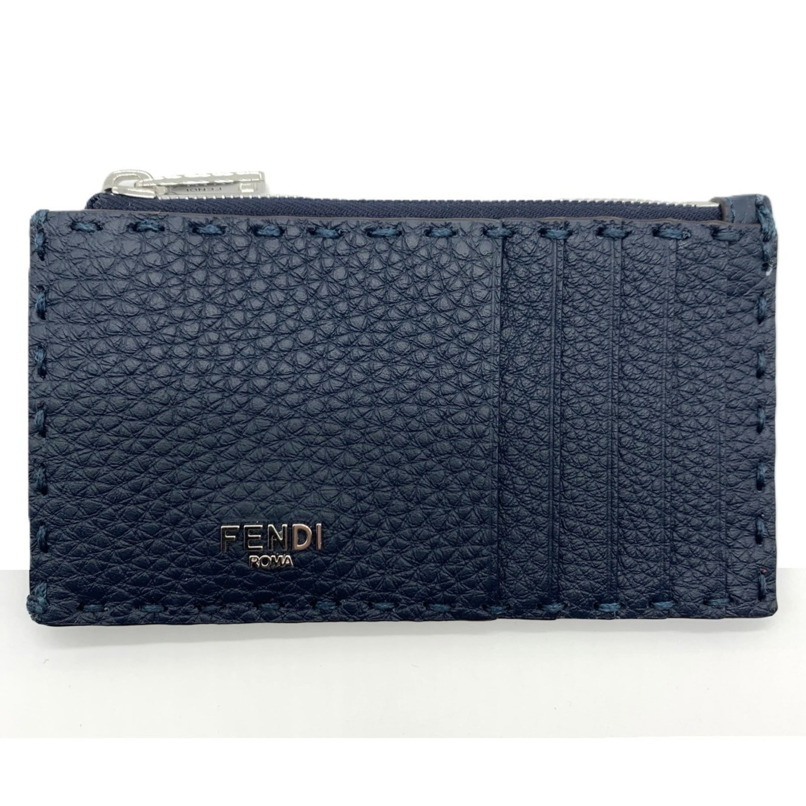 Coin purse leather case by Fendi: Coin purse leather case by Fendi The Fendi Selleria coin purse leather case boasts sleek, dark blue and red hues in its calfskin design. Measuring 7cm x 13cm x 1cm, it presents a compact yet stylish
