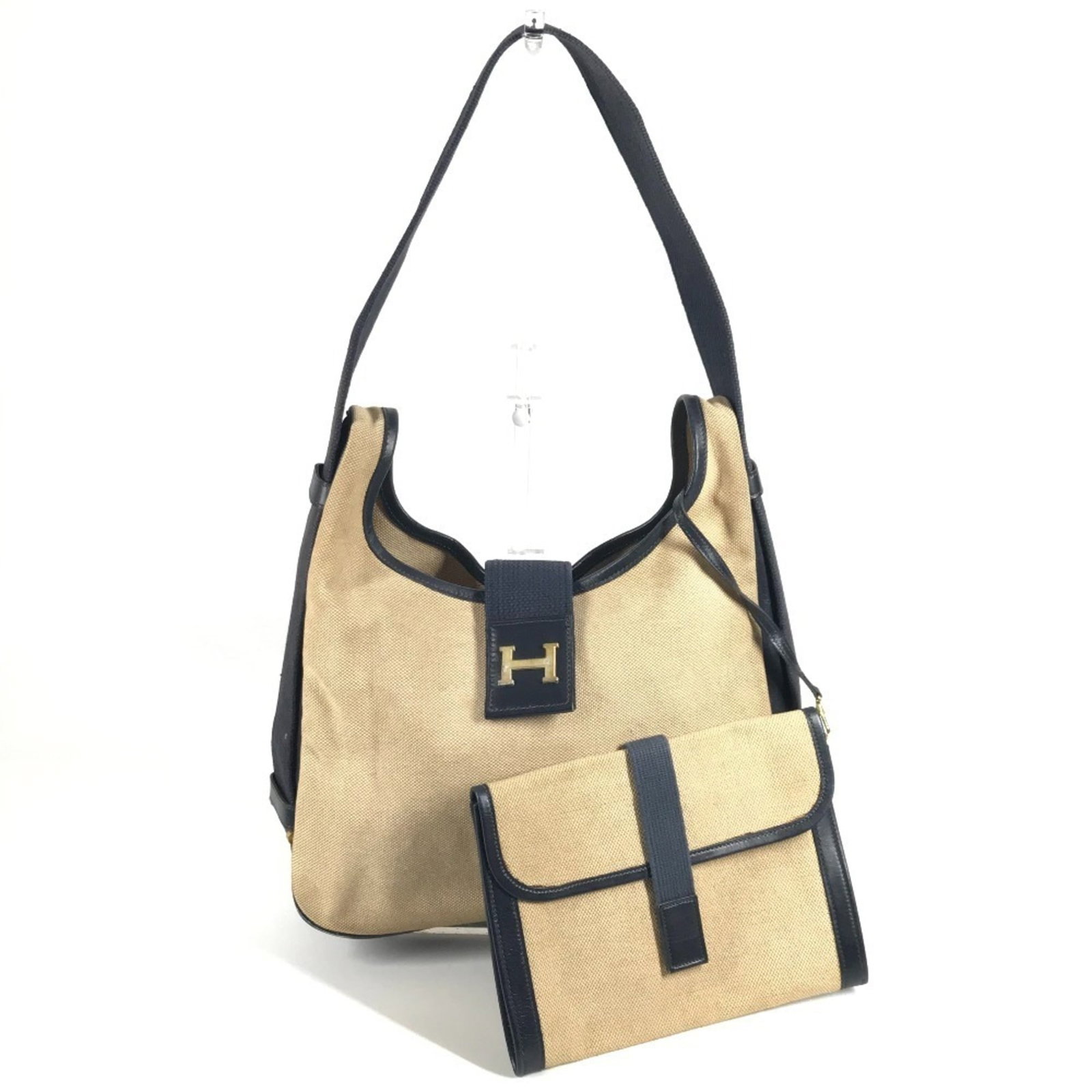 Canvas leather shoulder bag by Hermes: Canvas leather shoulder bag by Hermes Canvas leather shoulder bag by Hermes, featuring a classic design with a beige and navy color combination. This stylish bag measures 21cm x 27.5cm x 7cm, making i
