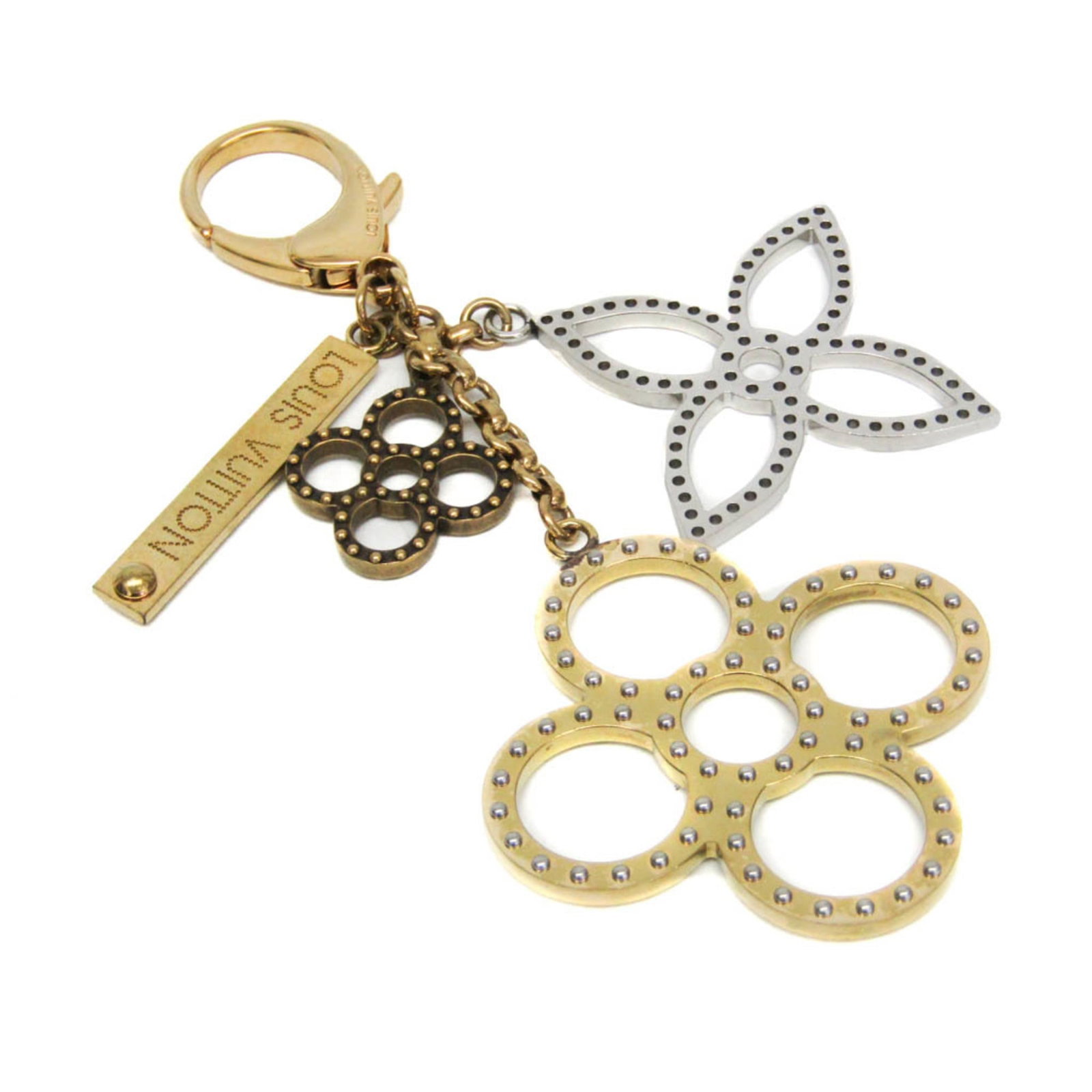 Keyring Metal By Louis Vuitton: Keyring Metal By Louis Vuitton Gold and Silver Keyring by Louis Vuitton. This metal keyring features the iconic Bijou Sac Tapage design, adding a touch of luxury to any outfit. Made from high-quality