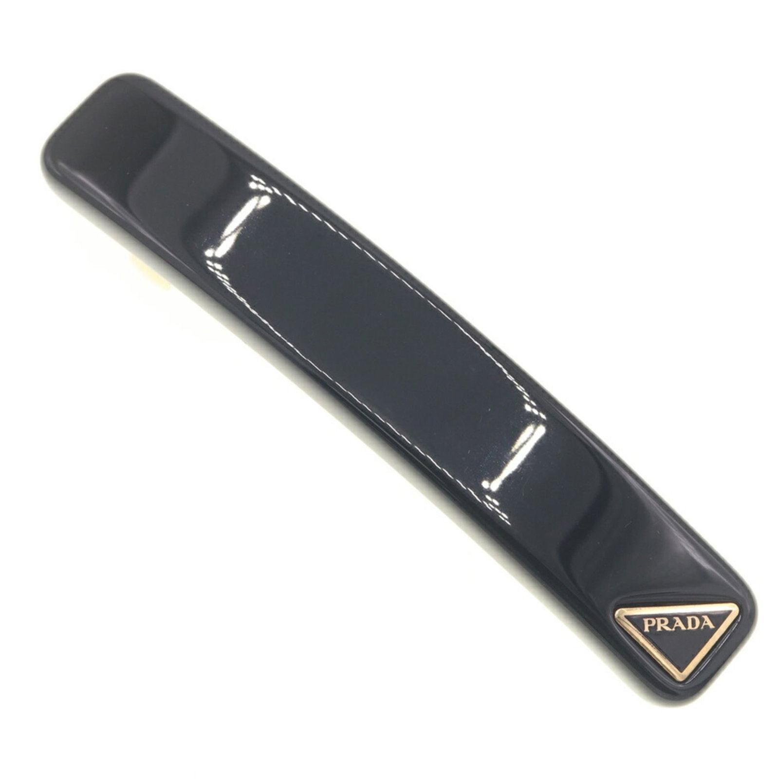 Prada Barrette Brass: Prada Barrette Brass Brass barrette from Prada, featuring a sleek black finish and measuring 1.5cm x 8cm in size, comes packaged in a box. This brass barrette bears the signature of the brand, Prada. 