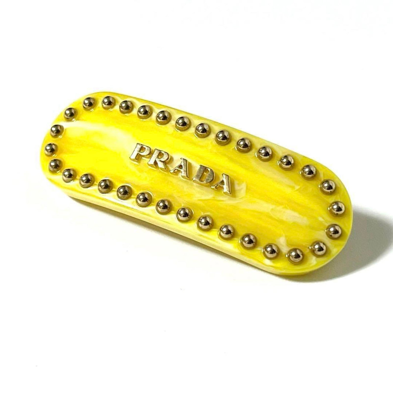 Metal plastic barrette by Prada: Metal plastic barrette by Prada Yellow metal and plastic barrette by Prada, measuring 7cm x 2.75'' in size. This barrette features a striking yellow color combination with metal and plastic materials.
