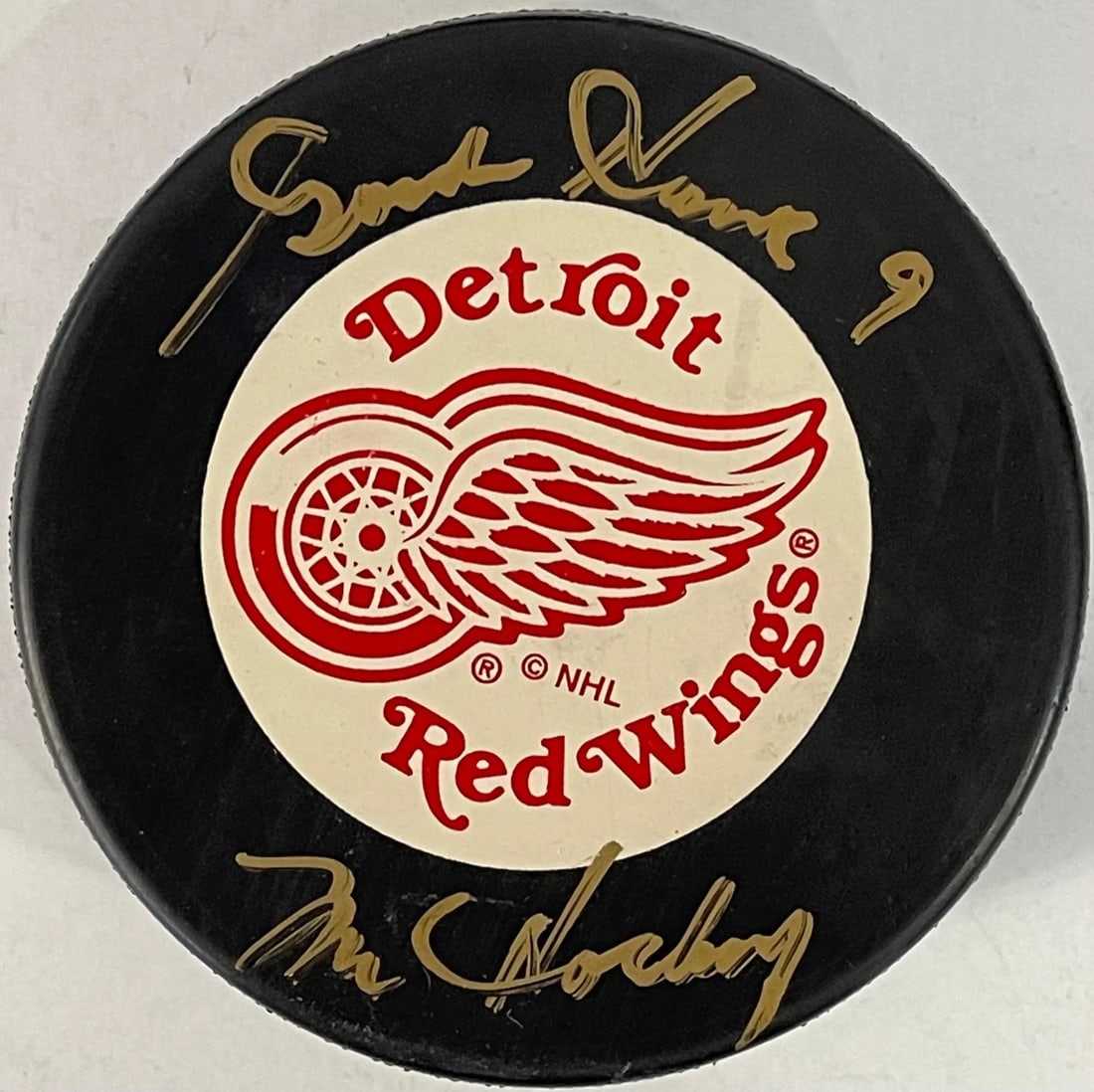 Gordie Howe Autographed Vintage Detroit Red Wings Puck: Gordie Howe Autographed Vintage Detroit Red Wings Puck Signed in gold sharpie across the front, this vintage Detroit Red Wings puck bears an inscription from Gordie Howe himself, "Mr Hockey". The puck