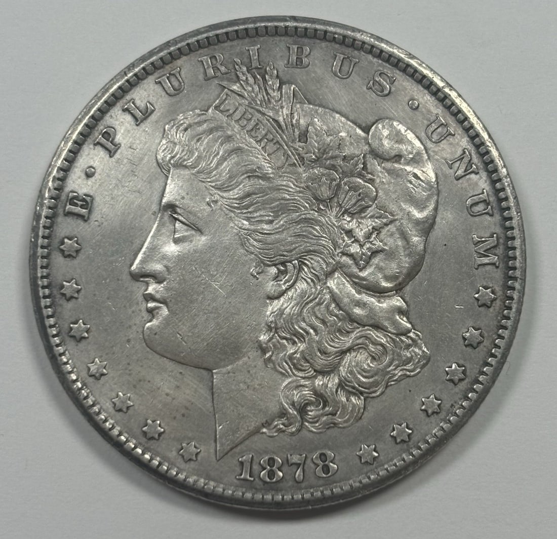 MORGAN DOLLAR CC RAW XF/ AU 1878: MORGAN DOLLAR CC RAW XF/ AU 1878 The Morgan Dollar, minted in 1878 at Carson City, boasts an XF/ AU condition, showcasing its raw beauty. This circulated coin is made of silver and features the iconic