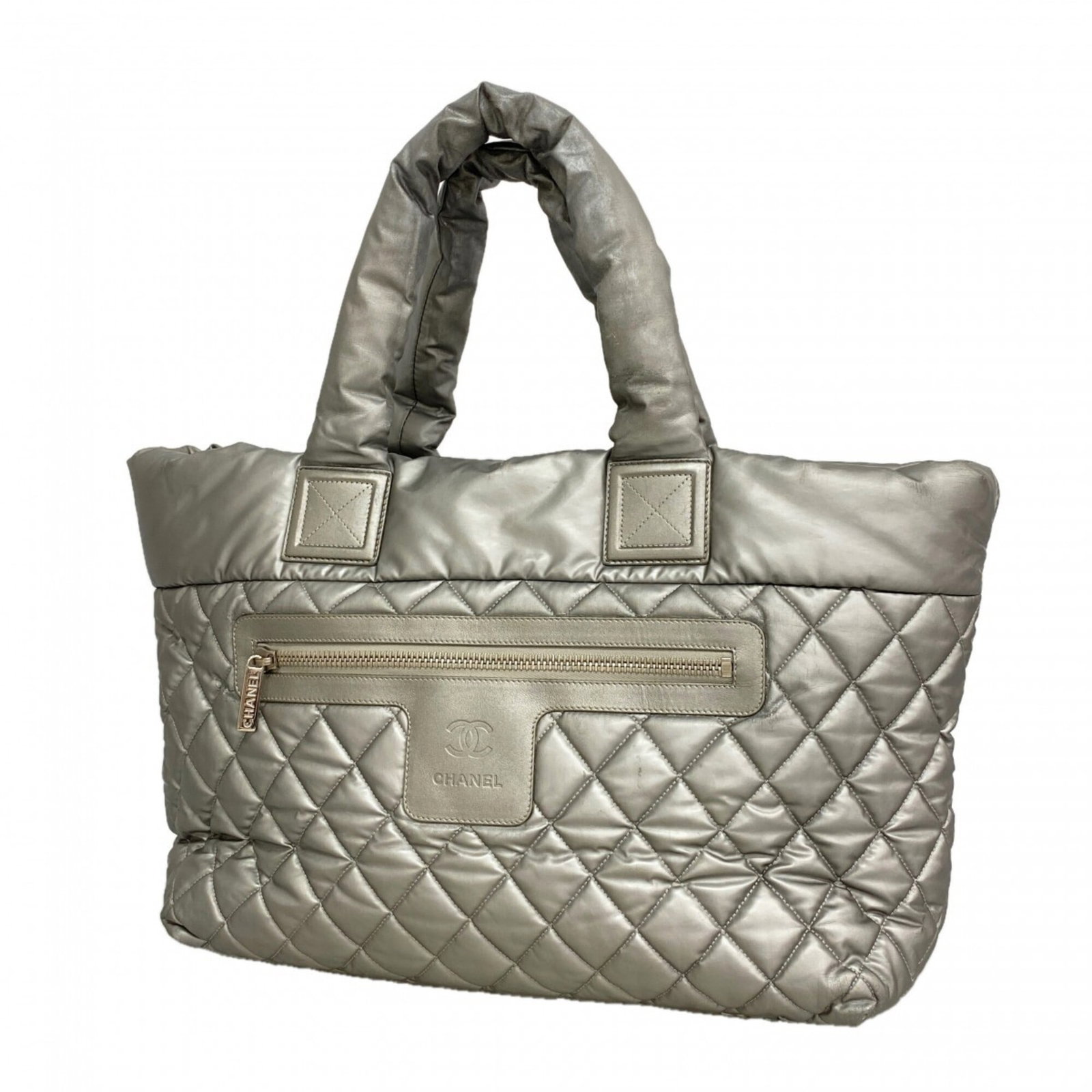 Nylon Tote Bag By Chanel: Nylon Tote Bag By Chanel Nylon Tote Bag By Chanel is made from high-quality nylon material and features a sleek gray color with silver hardware, adding a touch of sophistication to any outfit. The