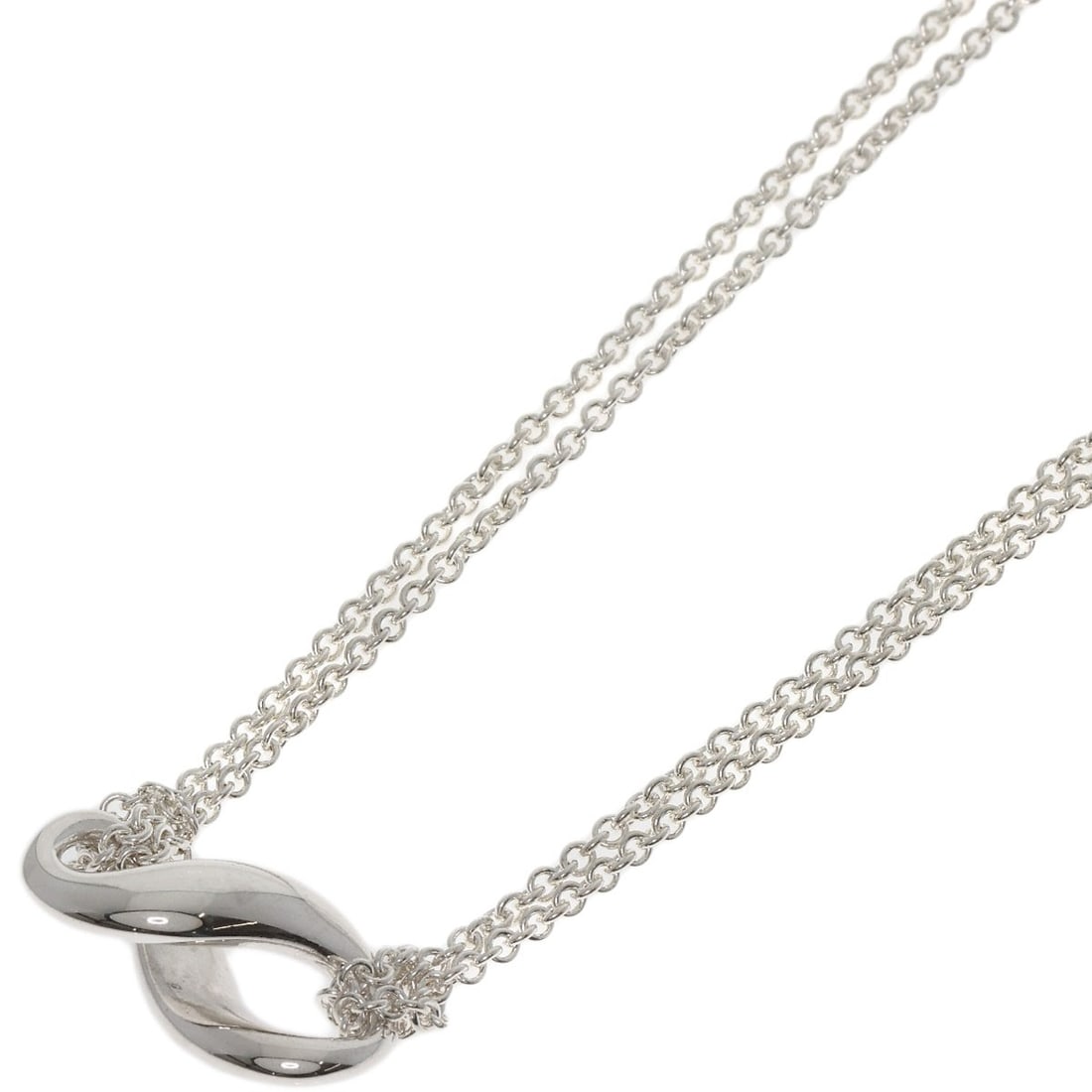 Figure eight necklace silver Tiffany Co: Figure eight necklace silver Tiffany Co Silver Tiffany Co. figure eight necklace, a sleek and modern design, features a striking silver metal exterior with no stone. Measuring 15.9 inches in length,
